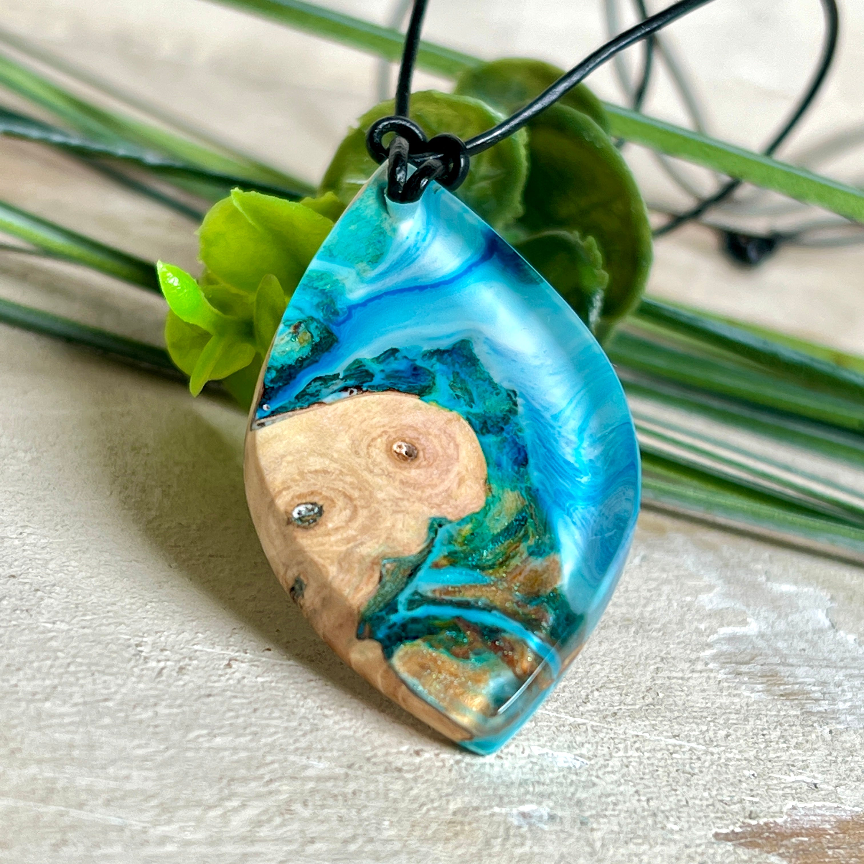 Handgefertigter Anhänger „Ocean Leaf“ aus Maserholz und Epoxidharz in Blau- und Türkistönen. Ein einzigartiges Schmuckstück, das die Schönheit von Natur und Meer einfängt. Mit verstellbarem Lederband (24–43 cm). Jeder Anhänger ist ein Unikat mit einzigartiger Maserung und Farbverlauf.