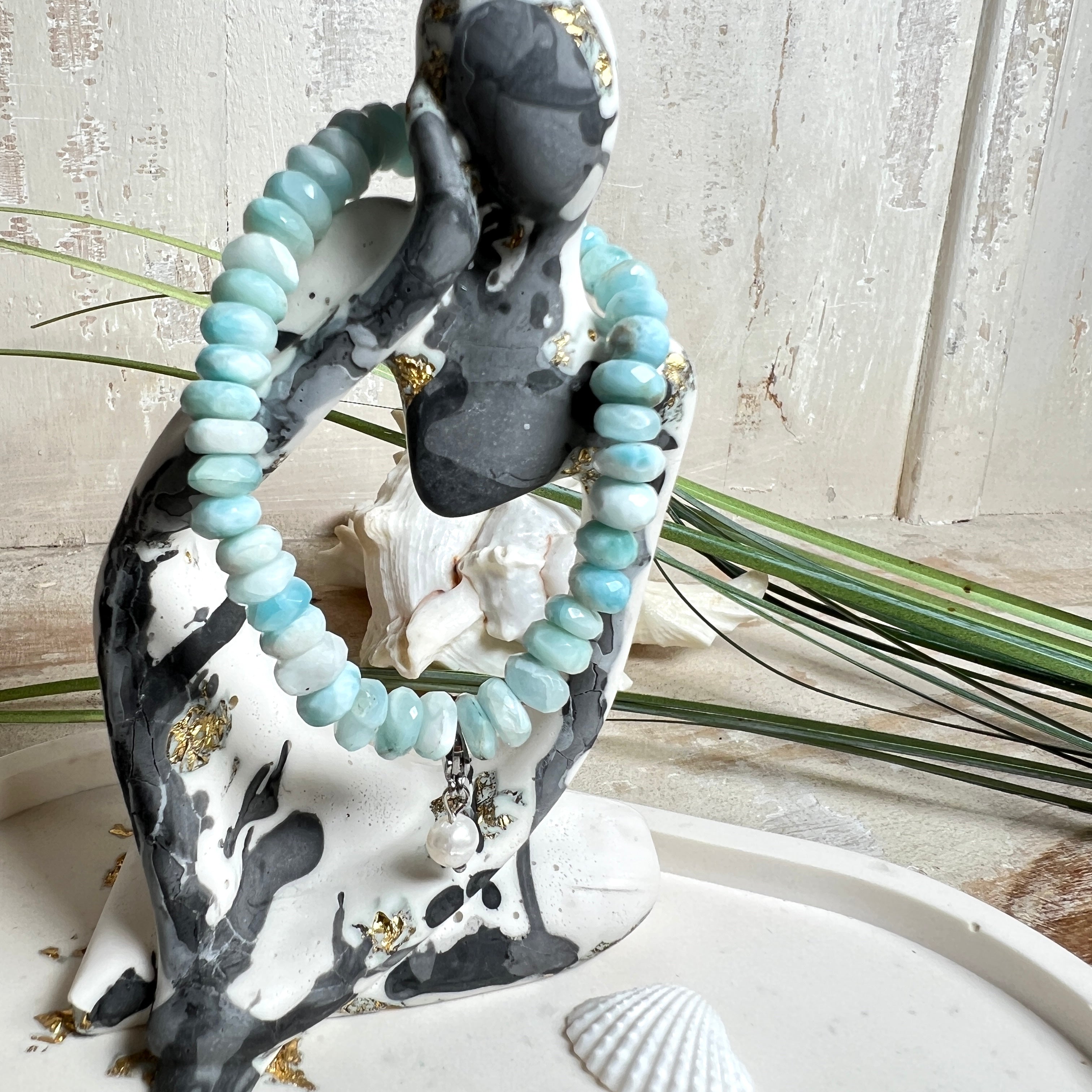 Handgefertigtes Armband aus seltenem Larimar mit facettierten, türkis-blauen Edelsteinperlen (Ø ca. 6–7 mm), elastischem Band und einem zarten Süßwasserperlen-Charm an Edelstahlkarabiner. Der wertvolle Larimar, auch „Stein des Atlantis“ genannt, gilt als Edelstein der Ruhe und Meeresverbundenheit.