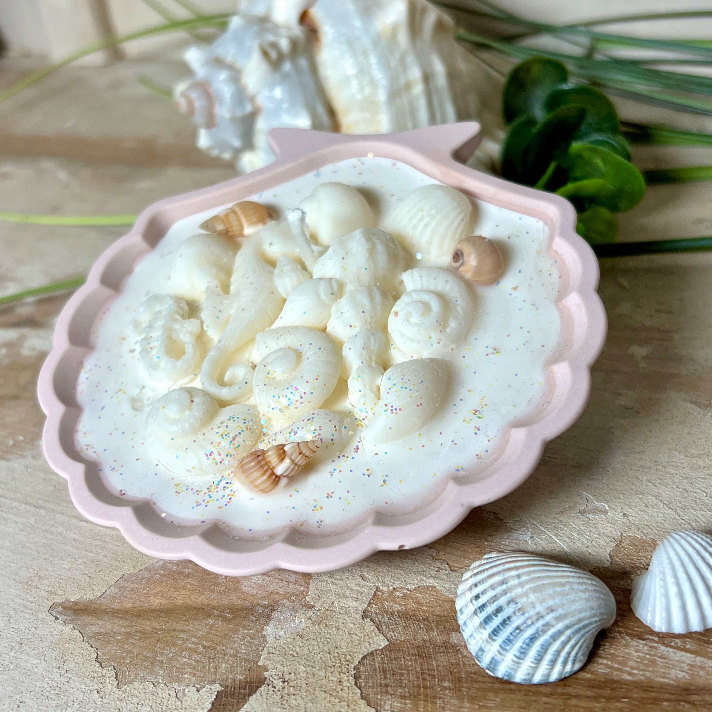 Handgefertigte Kerze „Meeresträume“ in einer Jesmonite-Schale (ca. 11 cm). Gefüllt mit nachhaltigem Sojawachs, verziert mit echten Muscheln, handgegossenen Wachsmuscheln und Seepferdchen. Feiner Glitzer sorgt für funkelnde Lichteffekte im Kerzenschein. Maritime Deko – edel, einzigartig & perfekt als Geschenk.