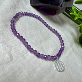 Handgefertigtes Amethyst-Armband aus facettierten 4 mm Edelstein-Perlen mit 925er Silber Charm „Blume des Lebens“. Spirituelles Schmuckstück in zartem Violett. Auf elastischem Gummiband, ca. 17 cm Innendurchmesser. Edles, fein gearbeitetes Design – ideal als Geschenk oder zur eigenen spirituellen Unterstützung.