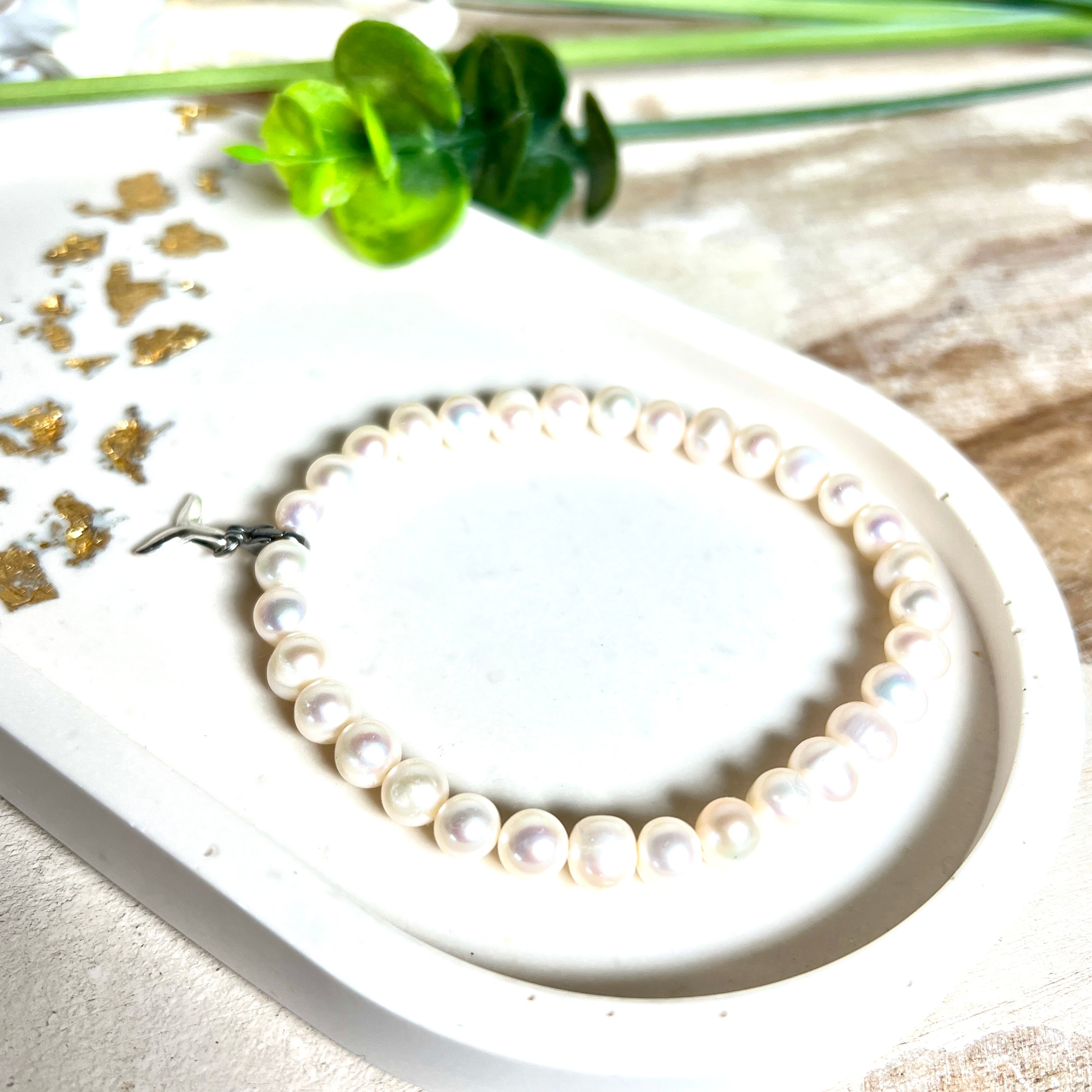 Handgefertigtes Armband aus echten Süßwasserperlen (ca. 6-7 mm), elastisch aufgezogen mit einem Edelstahl-Charm in Form einer Walflosse. Maritimes Design mit Bedeutung – stilvoll, natürlich und elegant. Größe ca. 17,5 cm. Ideal als Geschenk für Meeresliebhaberinnen oder für sich selbst.