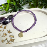 Handgefertigtes Amethyst-Armband mit facettierten 4 mm Edelstein-Perlen in zartem Violett, ergänzt durch einen vergoldeten 925 Silber Charm in Form der Blume des Lebens. Elastisches Design mit ca. 17 cm Innendurchmesser. Elegant, spirituell und fein – ein besonderes Schmuckstück für Achtsamkeit, Energie und Harmonie im Alltag.