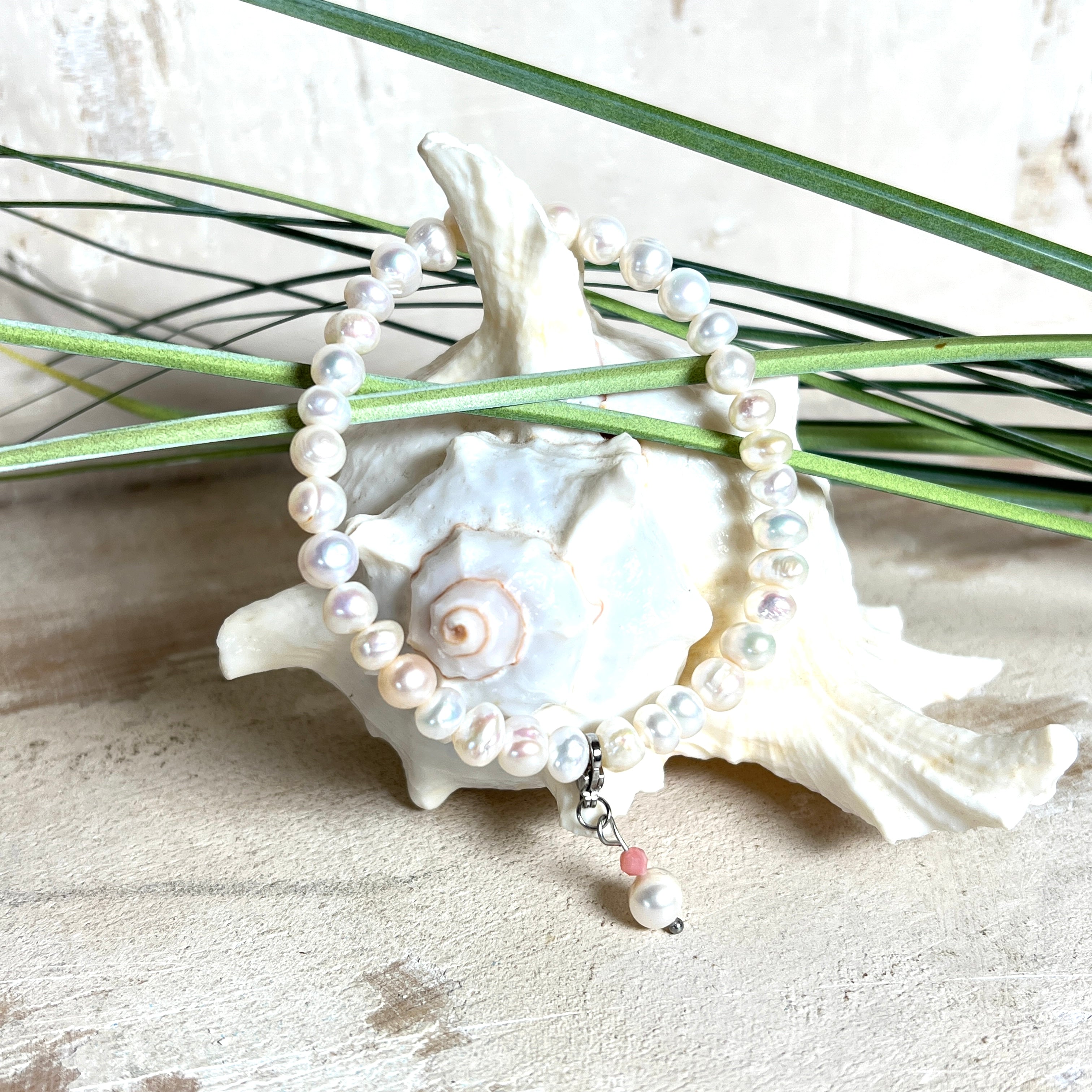 Handgefertigtes Armband „Ocean Bloom“ mit echten, schimmernden Süßwasserperlen (Ø ca. 6–7 mm) auf elastischem Band. Jede Perle ist ein Unikat mit natürlicher Form und sanftem Glanz. Highlight: Charmanhänger mit einer Süßwasserperle und einer facettierten Andenopal-Perle, befestigt an einem robusten Edelstahl-Karabiner. Ein Schmuckstück voller Eleganz, Symbolkraft und maritimer Schönheit.