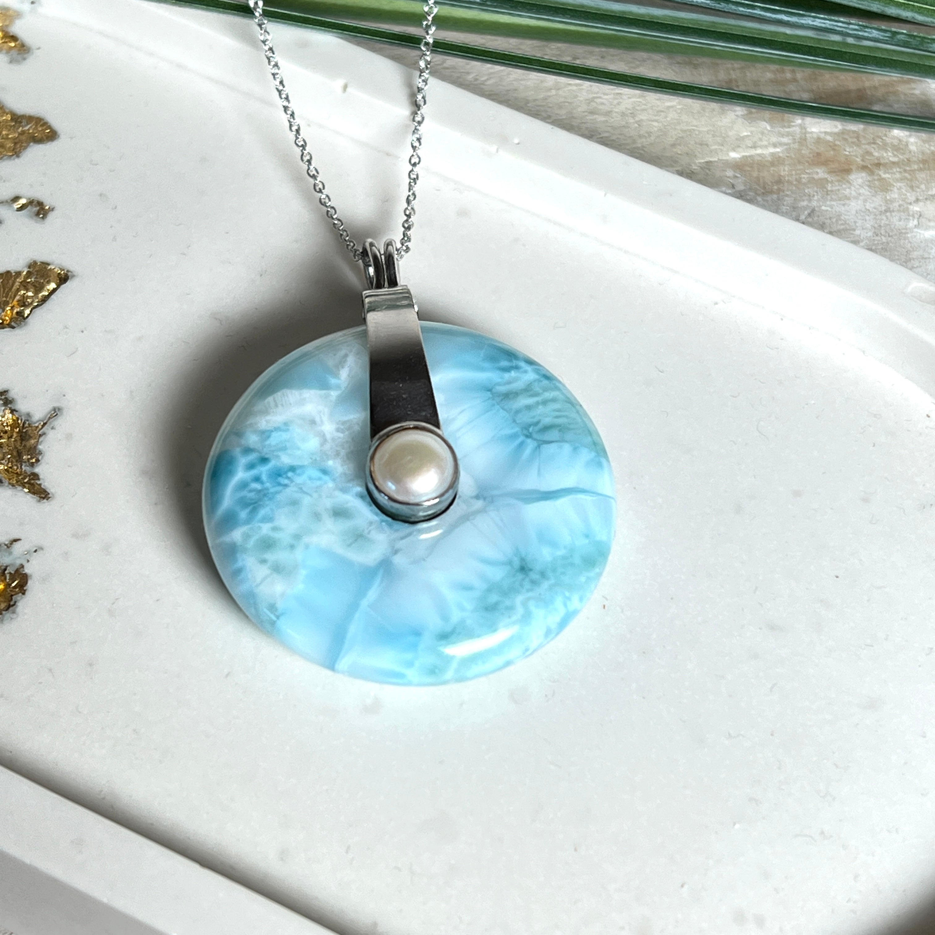 Echter Larimar-Donut (42 mm) mit Süßwasserperle, gefasst in rhodiniertem 925 Sterlingsilber. Mit 45 cm langer, rhodinierter Silberkette. Selten, edel & handgefertigt – inspiriert vom Blau der Karibik.