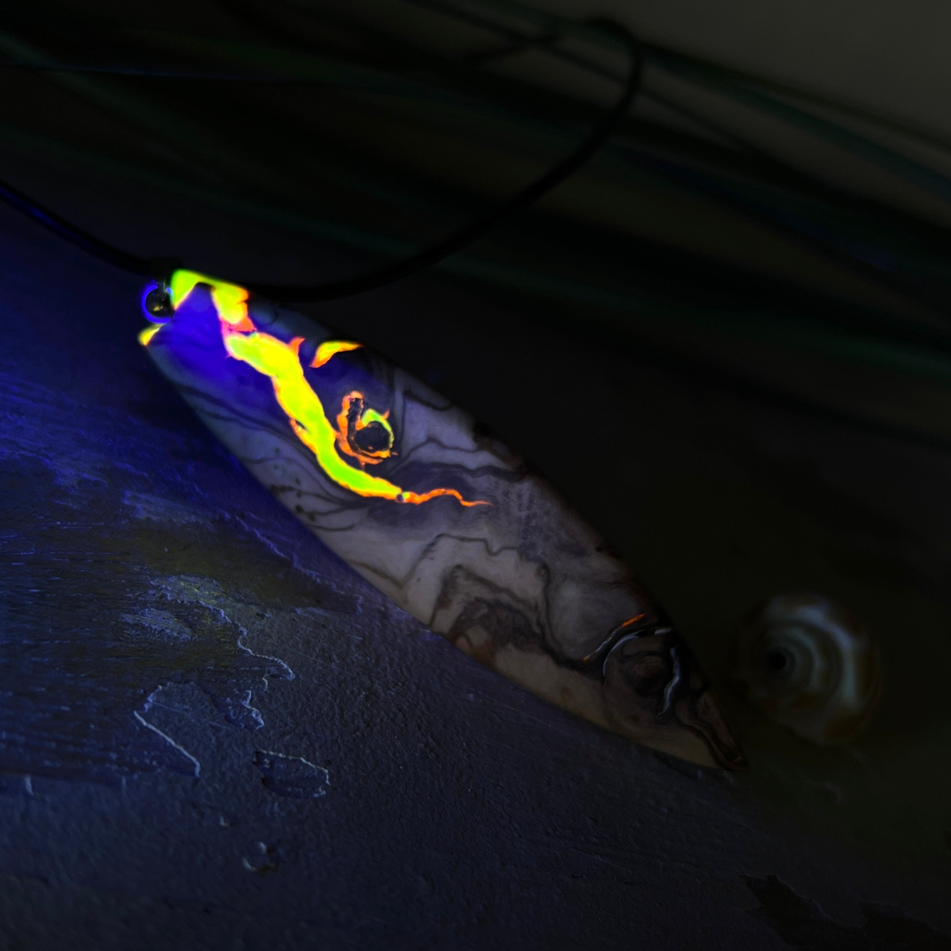 Handgefertigter Surfbrett-Anhänger aus Olivenholz und fluoreszierendem Harz in Gelb und Orange. Das leuchtende Harz beginnt unter Schwarzlicht intensiv zu strahlen und macht den Anhänger zu einem echten Highlight. Größe ca. 6,3 × 2 cm, mit Edelstahl-Anhängerschlaufe und Lederkette mit Edelstahlverschluss und 5 cm Verlängerung. Jedes Schmuckstück ist ein Unikat – Maserung und Farbspiel sind einzigartig. Ideal für Naturliebhaber und Individualisten.
