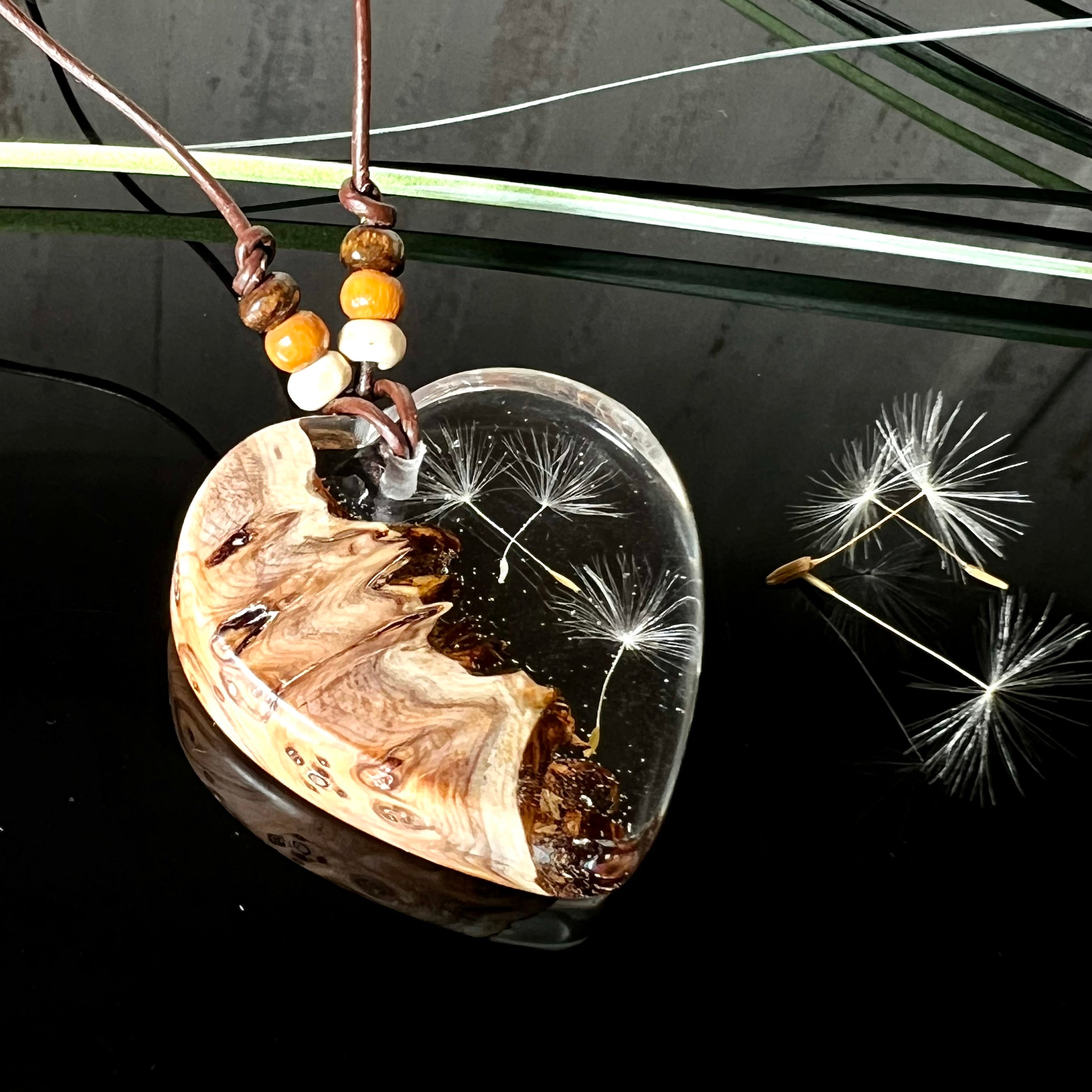 Handgefertigter Herzanhänger Pusteblumenzauber aus Maserholz und klarem Epoxidharz mit echter Pusteblume. Das Design vereint natürliche Maserstrukturen mit der Leichtigkeit schwebender Pusteblumenschirmchen – ein edles, naturverbundenes Schmuckstück mit Symbolkraft. Ideal für Naturliebhaber, Träumer und alle, die das Besondere suchen.