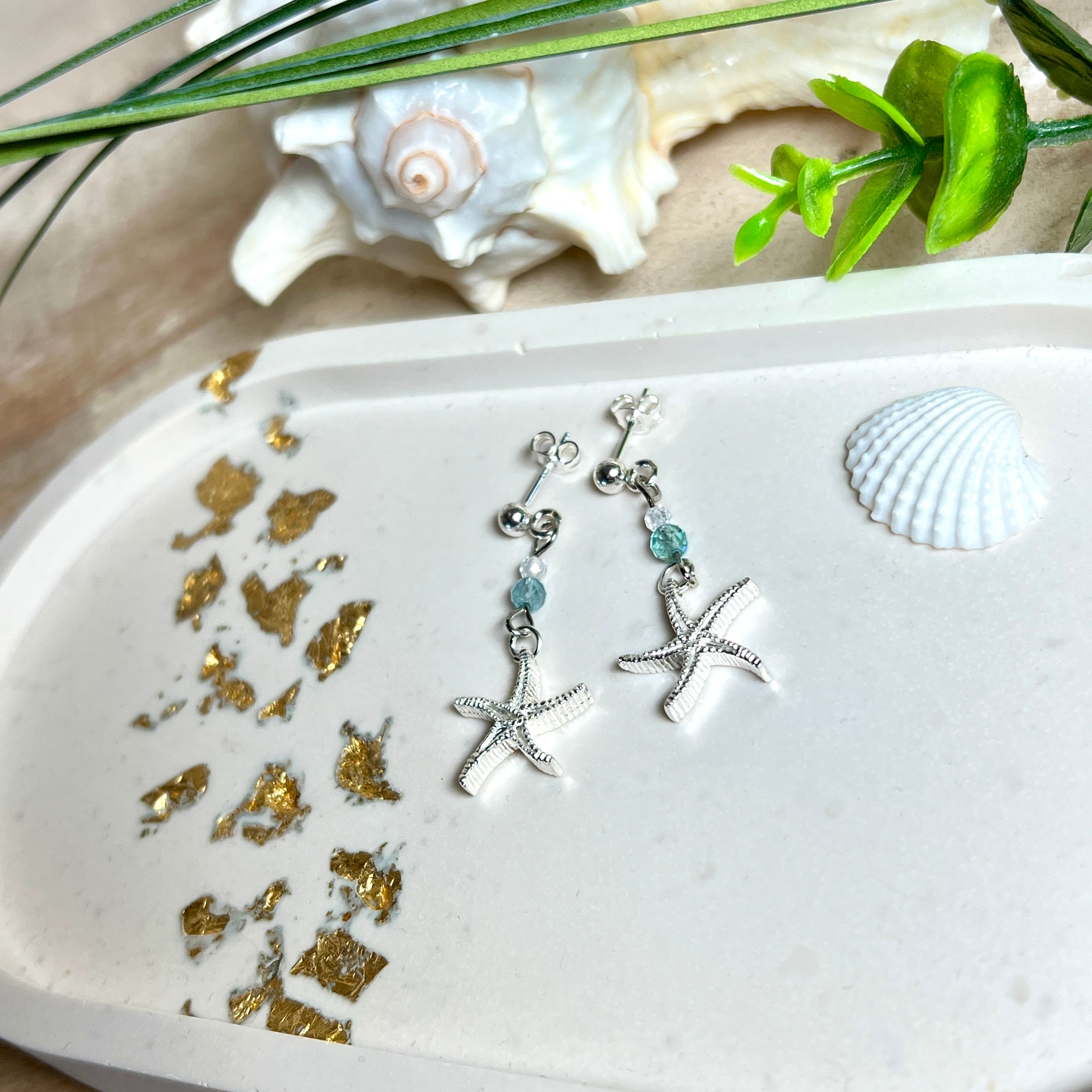 Edle „Ocean Star“ Ohrringe aus 925 Sterling Silber mit Seestern-Anhängern (18 × 17 mm), verziert mit einer aquablauen Apatitperle und funkelndem Zirkonia. Länge getragen: 45 mm. Maritime Schmuckstücke, die das Funkeln des Meeres einfangen – elegant, hochwertig und ein ideales Geschenk für Meeresliebhaber und Sommerträume.