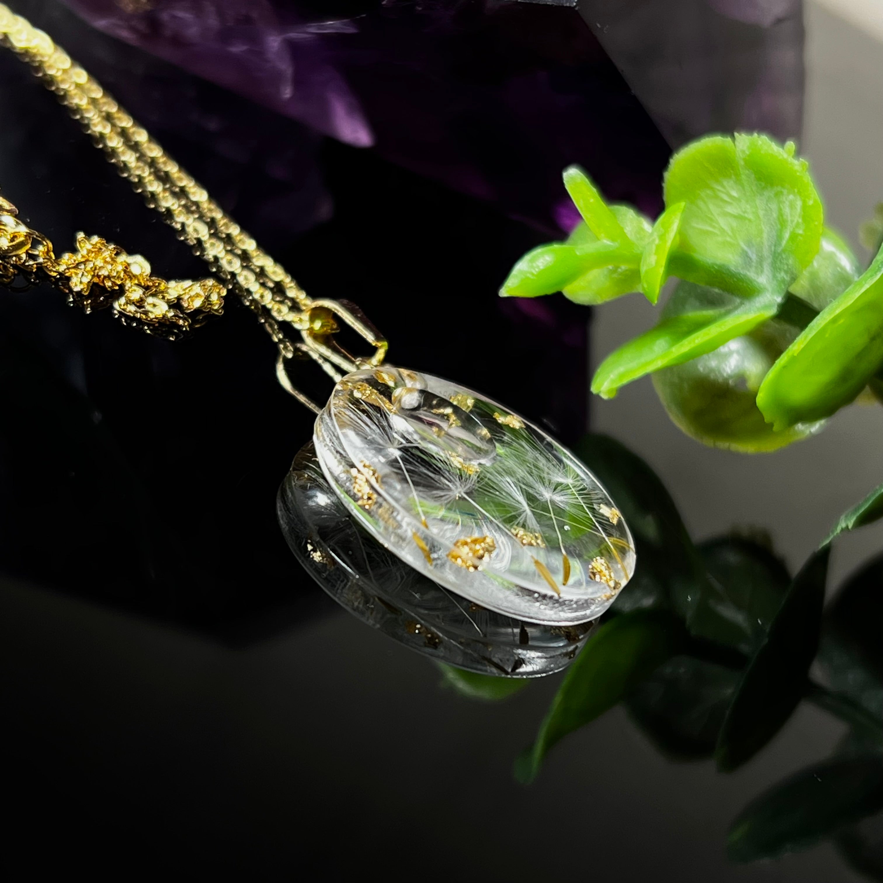 Runder Harzanhänger mit echten Pusteblumensamen und zarten Blattgold-Akzenten auf einer vergoldeten 925 Silberkette, 45 cm lang. Der Anhänger hat einen Durchmesser von ca. 2,6 cm und wird von einer goldfarbenen Edelstahlöse gehalten. Das Design symbolisiert Leichtigkeit, Hoffnung und Naturverbundenheit – perfekt als Geschenk oder für Naturliebhaberinnen. Liebevoll von Hand gefertigt und ein echtes Unikat.