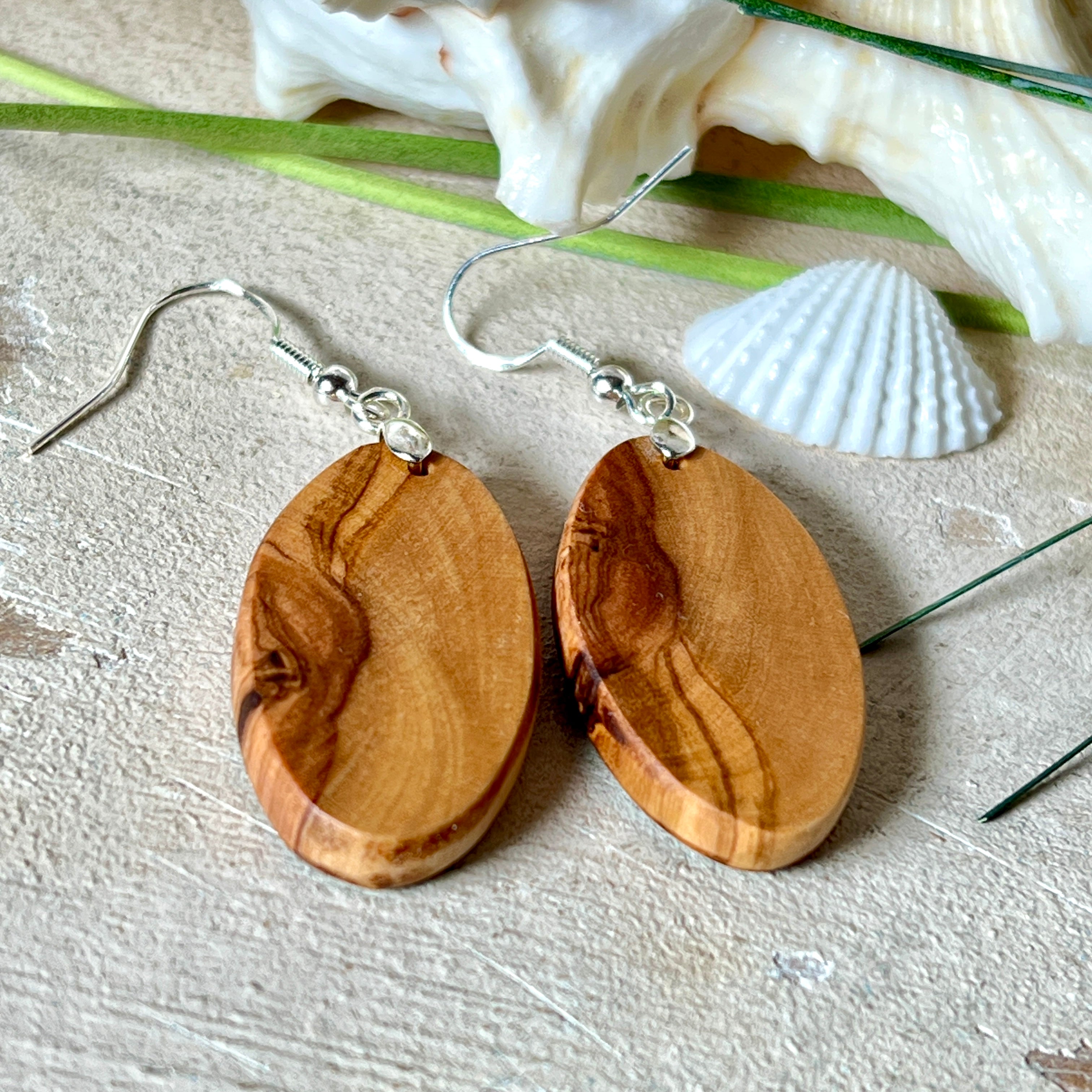 Handgefertigte Ohrringe „Wave Harmony“ aus Olivenholz und Epoxidharz in Blau-, Türkis- und Weißtönen. Das Design erinnert an Meereswellen am Strand. Jeder Ohrring ist ein Unikat mit individueller Maserung. Versilberte, nickelfreie und bleifreie Anhängerschlaufe, 925 Silber Ohrhaken. Maritimer Schmuck – perfekt für Meerliebhaber und als edles Geschenk.