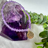 Handgefertigtes Amethyst-Armband mit facettierten 4 mm Edelstein-Perlen in zartem Violett, ergänzt durch einen vergoldeten 925 Silber Charm in Form der Blume des Lebens. Elastisches Design mit ca. 17 cm Innendurchmesser. Elegant, spirituell und fein – ein besonderes Schmuckstück für Achtsamkeit, Energie und Harmonie im Alltag.