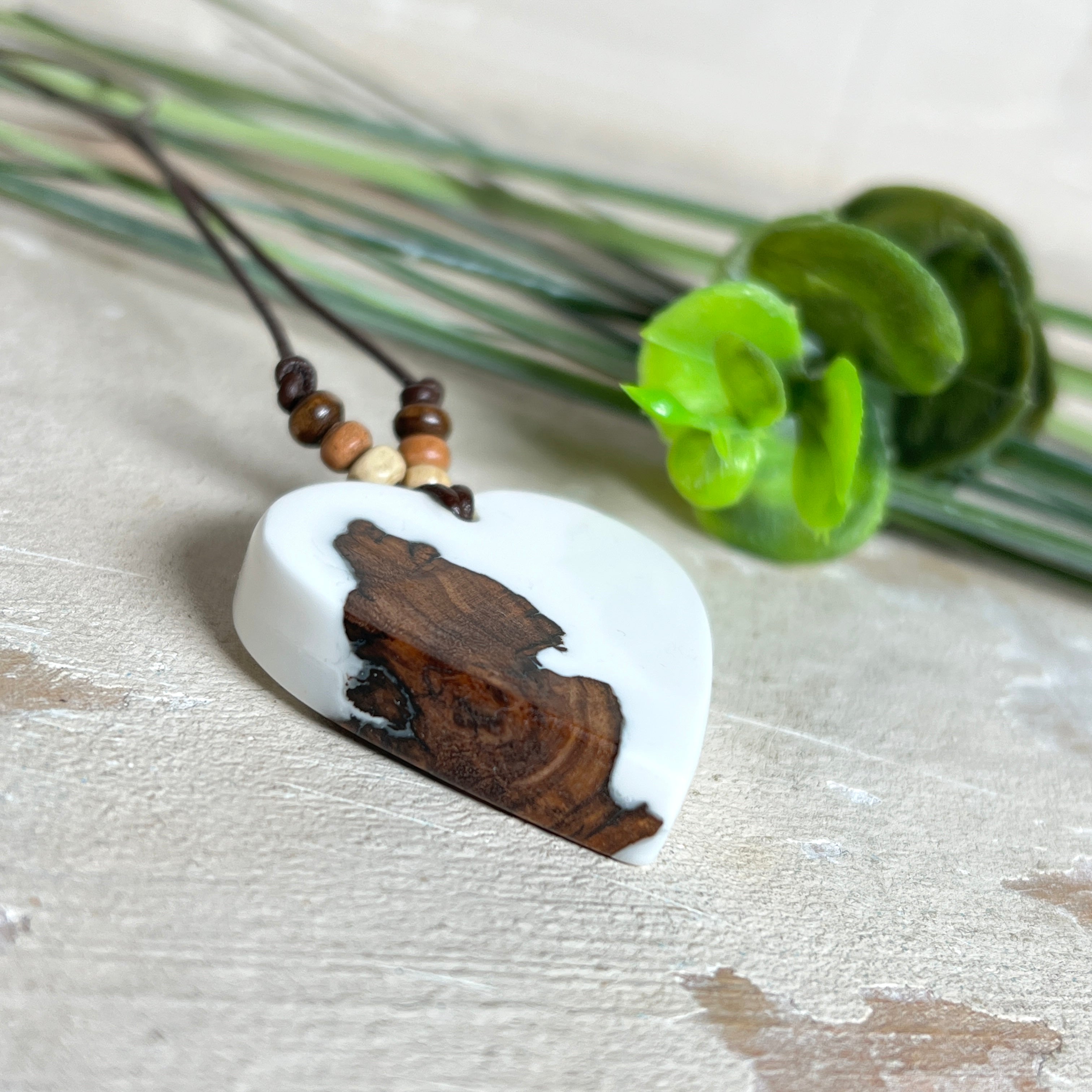 Herzanhänger „Pure Heart“ aus Maserholz und weißem Epoxidharz. Handgefertigtes Unikat mit kontrastreichem Design – die natürliche Maserung des Holzes trifft auf die klare Reinheit von Weiß. Größe ca. 3,5 × 3,5 cm. Verstellbares Lederband (23–41 cm) mit Holzperlen. Ein edles Schmuckstück, inspiriert von Natur und Liebe.