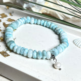 Handgefertigtes Armband aus seltenem Larimar mit facettierten, türkis-blauen Edelsteinperlen (Ø ca. 6–7 mm), elastischem Band und einem zarten Süßwasserperlen-Charm an Edelstahlkarabiner. Der wertvolle Larimar, auch „Stein des Atlantis“ genannt, gilt als Edelstein der Ruhe und Meeresverbundenheit.