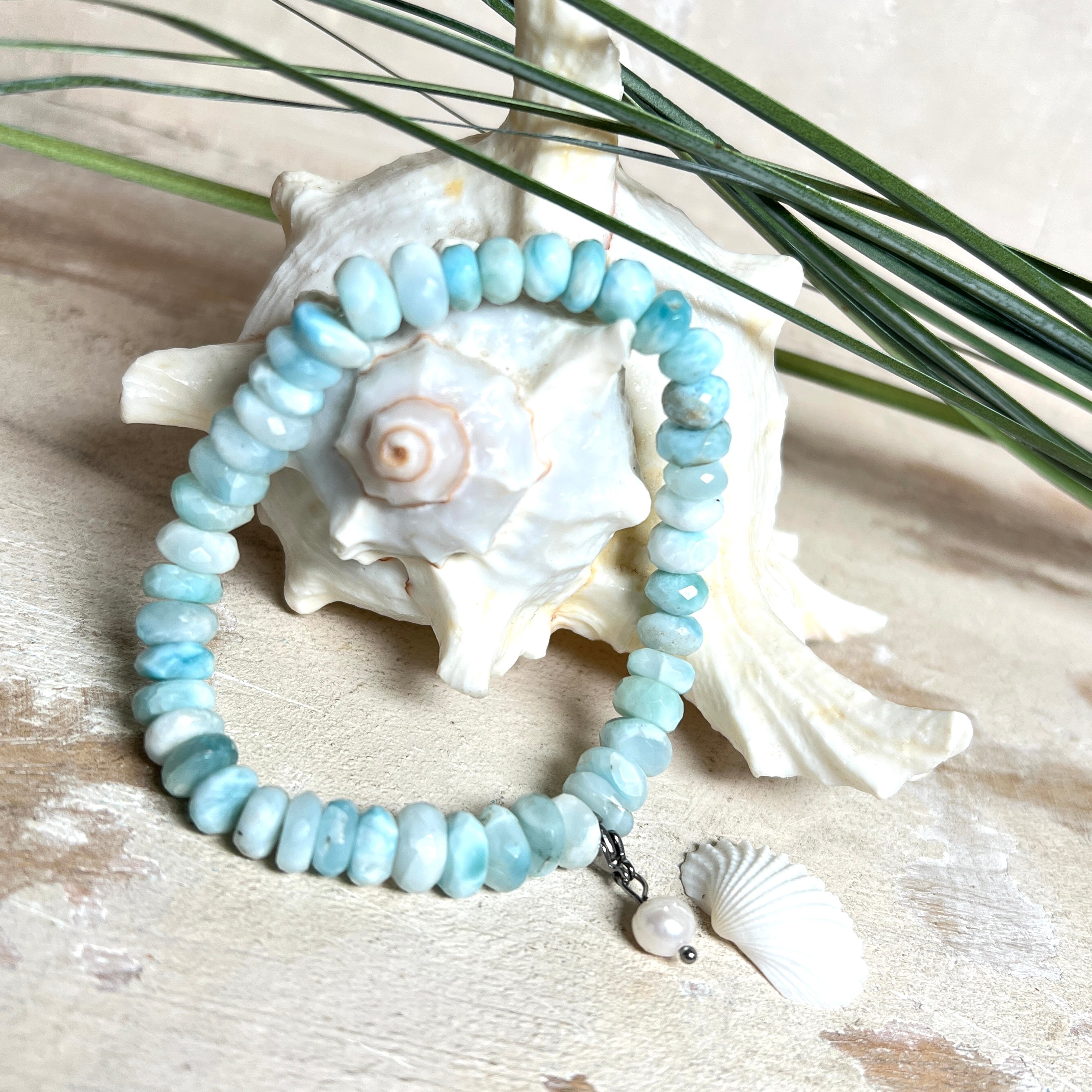 Handgefertigtes Armband aus seltenem Larimar mit facettierten, türkis-blauen Edelsteinperlen (Ø ca. 6–7 mm), elastischem Band und einem zarten Süßwasserperlen-Charm an Edelstahlkarabiner. Der wertvolle Larimar, auch „Stein des Atlantis“ genannt, gilt als Edelstein der Ruhe und Meeresverbundenheit.