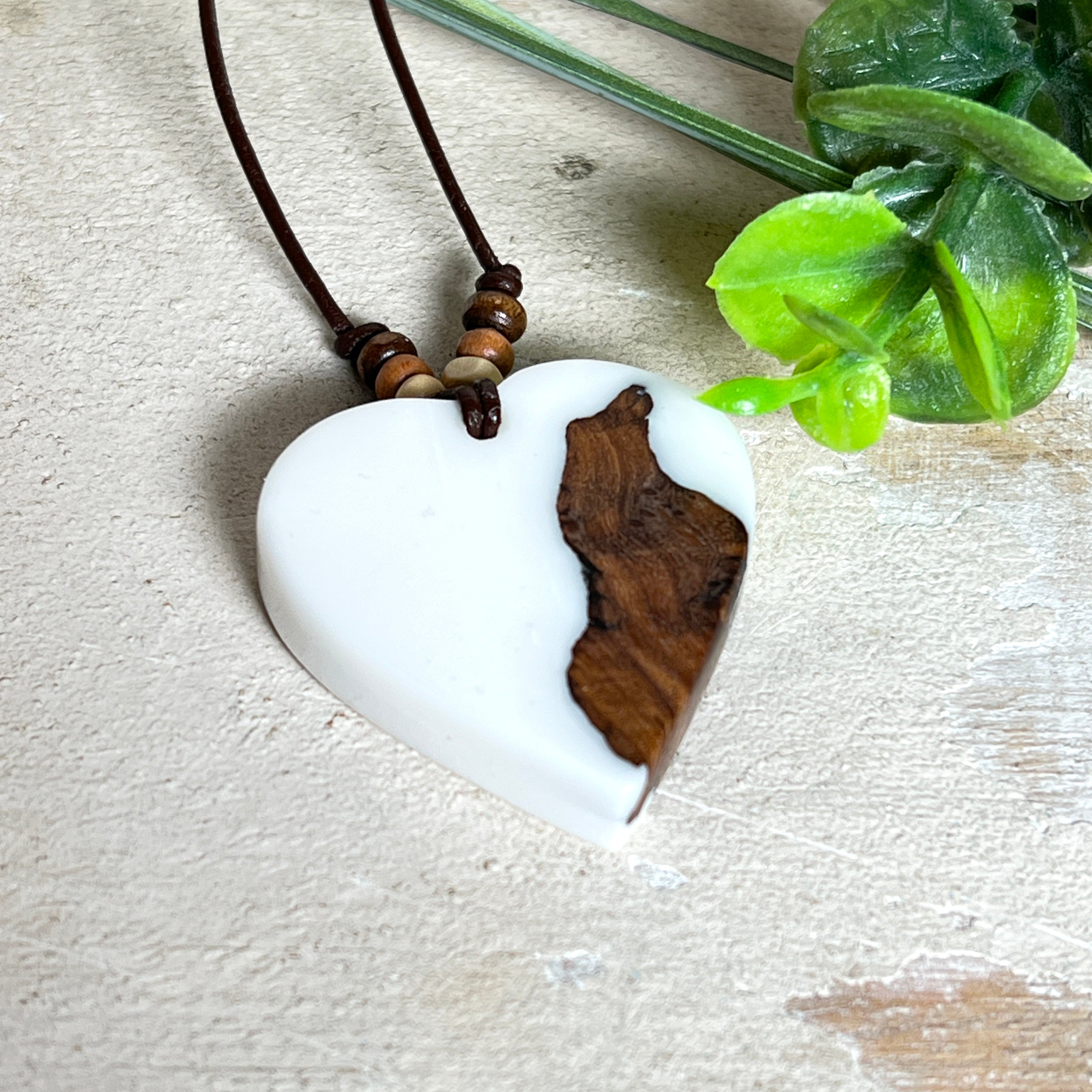 Herzanhänger „Pure Heart“ aus Maserholz und weißem Epoxidharz. Handgefertigtes Unikat mit kontrastreichem Design – die natürliche Maserung des Holzes trifft auf die klare Reinheit von Weiß. Größe ca. 3,5 × 3,5 cm. Verstellbares Lederband (23–41 cm) mit Holzperlen. Ein edles Schmuckstück, inspiriert von Natur und Liebe.