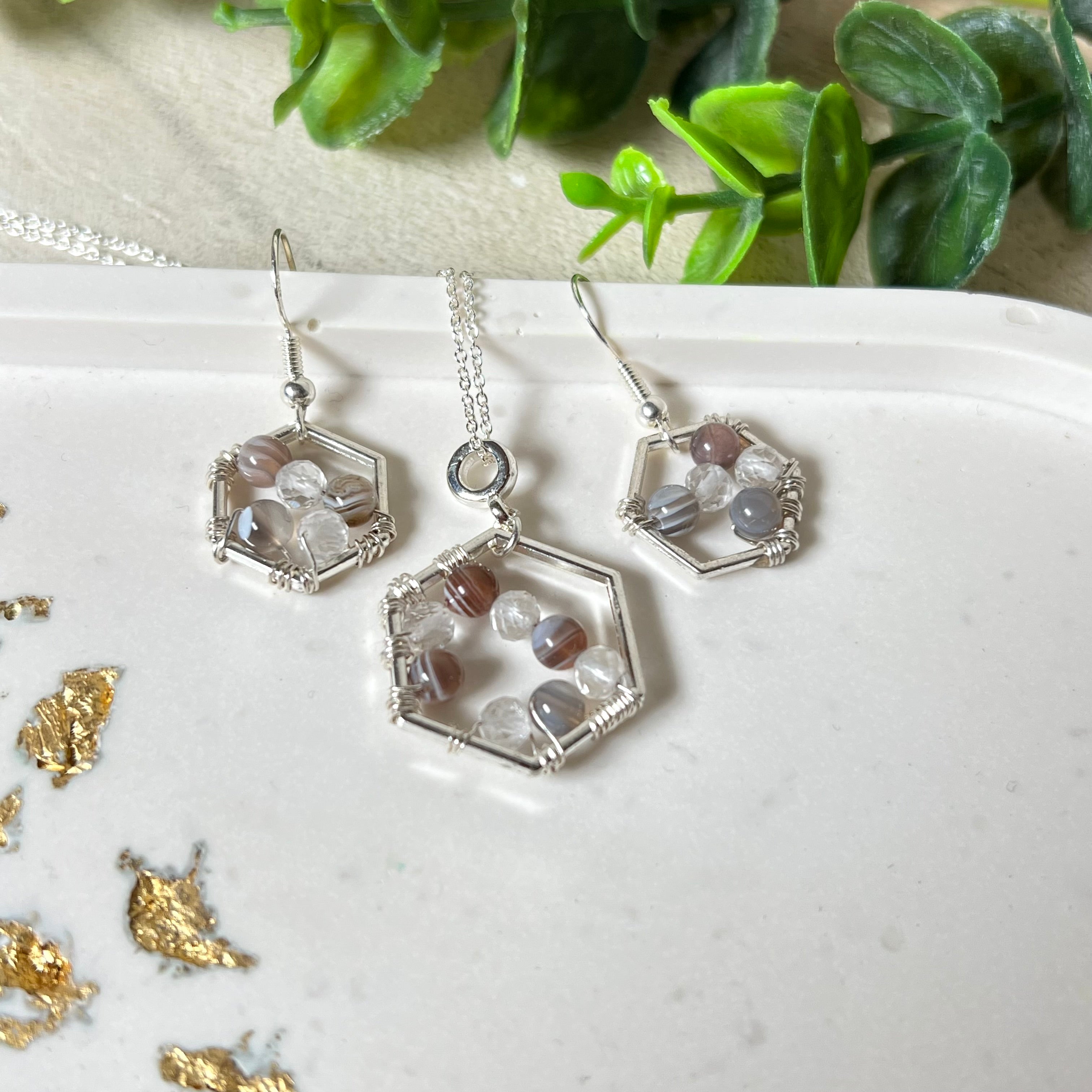 “Das Schmuckset bestehend aus 925 Silber Halskette und Ohrringen mit Botswana-Achat und facettierten Bergkristallperlen, stilvoll eingefasst in versilberte Edelstahl-Lünetten. Elegantes Design für besondere Anlässe oder den Alltag.”