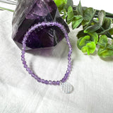 Handgefertigtes Amethyst-Armband aus facettierten 4 mm Edelstein-Perlen mit 925er Silber Charm „Blume des Lebens“. Spirituelles Schmuckstück in zartem Violett. Auf elastischem Gummiband, ca. 17 cm Innendurchmesser. Edles, fein gearbeitetes Design – ideal als Geschenk oder zur eigenen spirituellen Unterstützung.