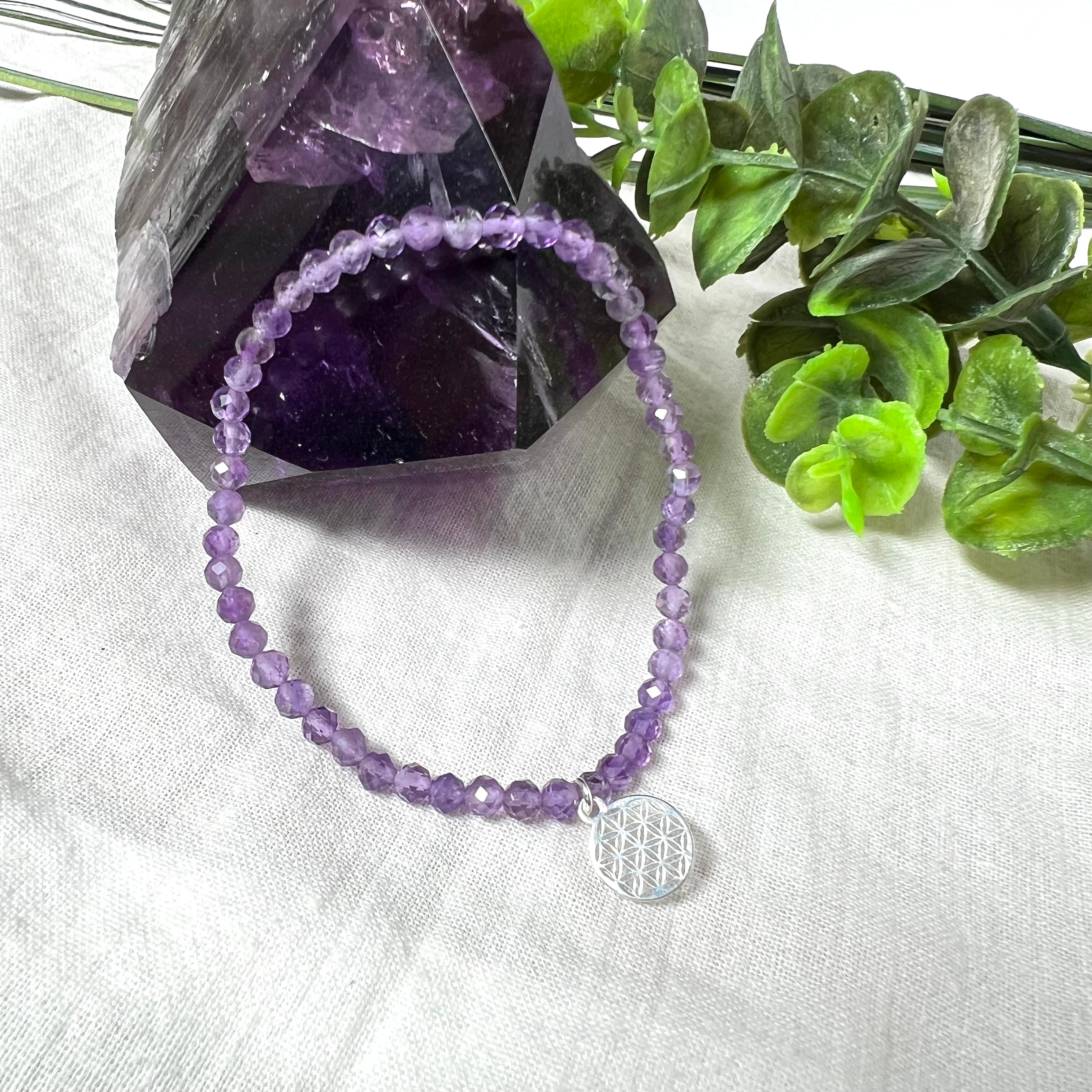 Handgefertigtes Amethyst-Armband aus facettierten 4 mm Edelstein-Perlen mit 925er Silber Charm „Blume des Lebens“. Spirituelles Schmuckstück in zartem Violett. Auf elastischem Gummiband, ca. 17 cm Innendurchmesser. Edles, fein gearbeitetes Design – ideal als Geschenk oder zur eigenen spirituellen Unterstützung.
