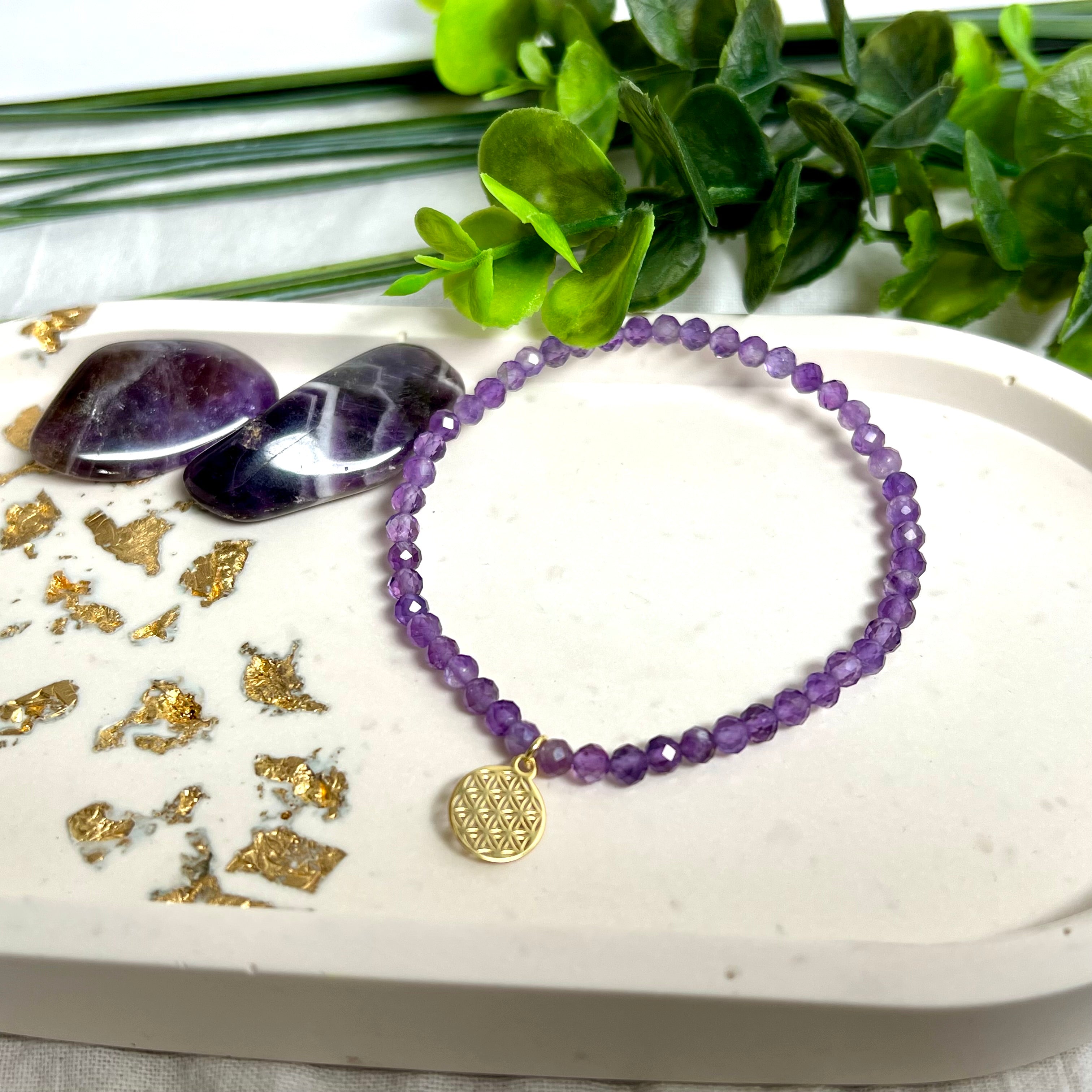 Handgefertigtes Amethyst-Armband mit facettierten 4 mm Edelstein-Perlen in zartem Violett, ergänzt durch einen vergoldeten 925 Silber Charm in Form der Blume des Lebens. Elastisches Design mit ca. 17 cm Innendurchmesser. Elegant, spirituell und fein – ein besonderes Schmuckstück für Achtsamkeit, Energie und Harmonie im Alltag.