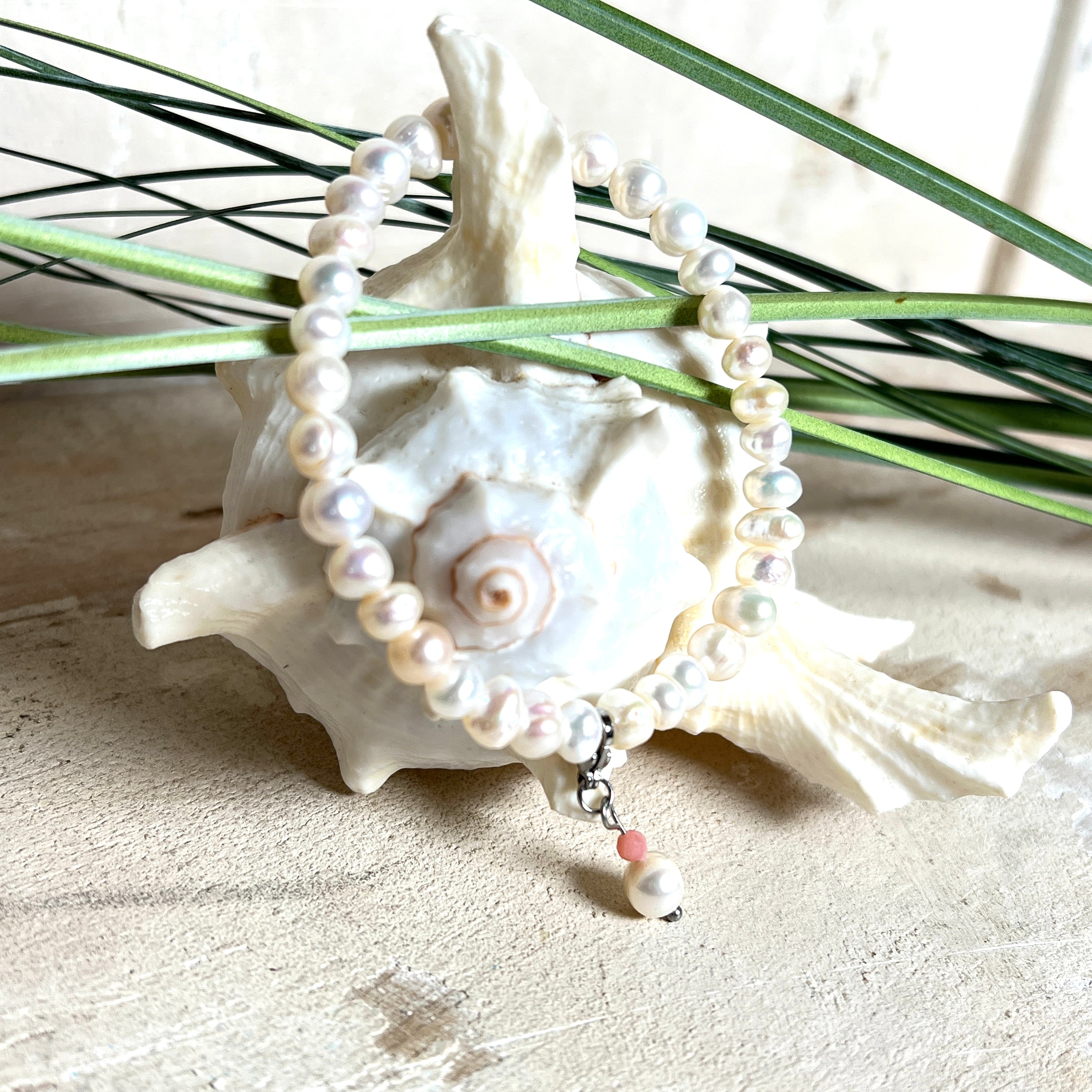 Handgefertigtes Armband „Ocean Bloom“ mit echten, schimmernden Süßwasserperlen (Ø ca. 6–7 mm) auf elastischem Band. Jede Perle ist ein Unikat mit natürlicher Form und sanftem Glanz. Highlight: Charmanhänger mit einer Süßwasserperle und einer facettierten Andenopal-Perle, befestigt an einem robusten Edelstahl-Karabiner. Ein Schmuckstück voller Eleganz, Symbolkraft und maritimer Schönheit.