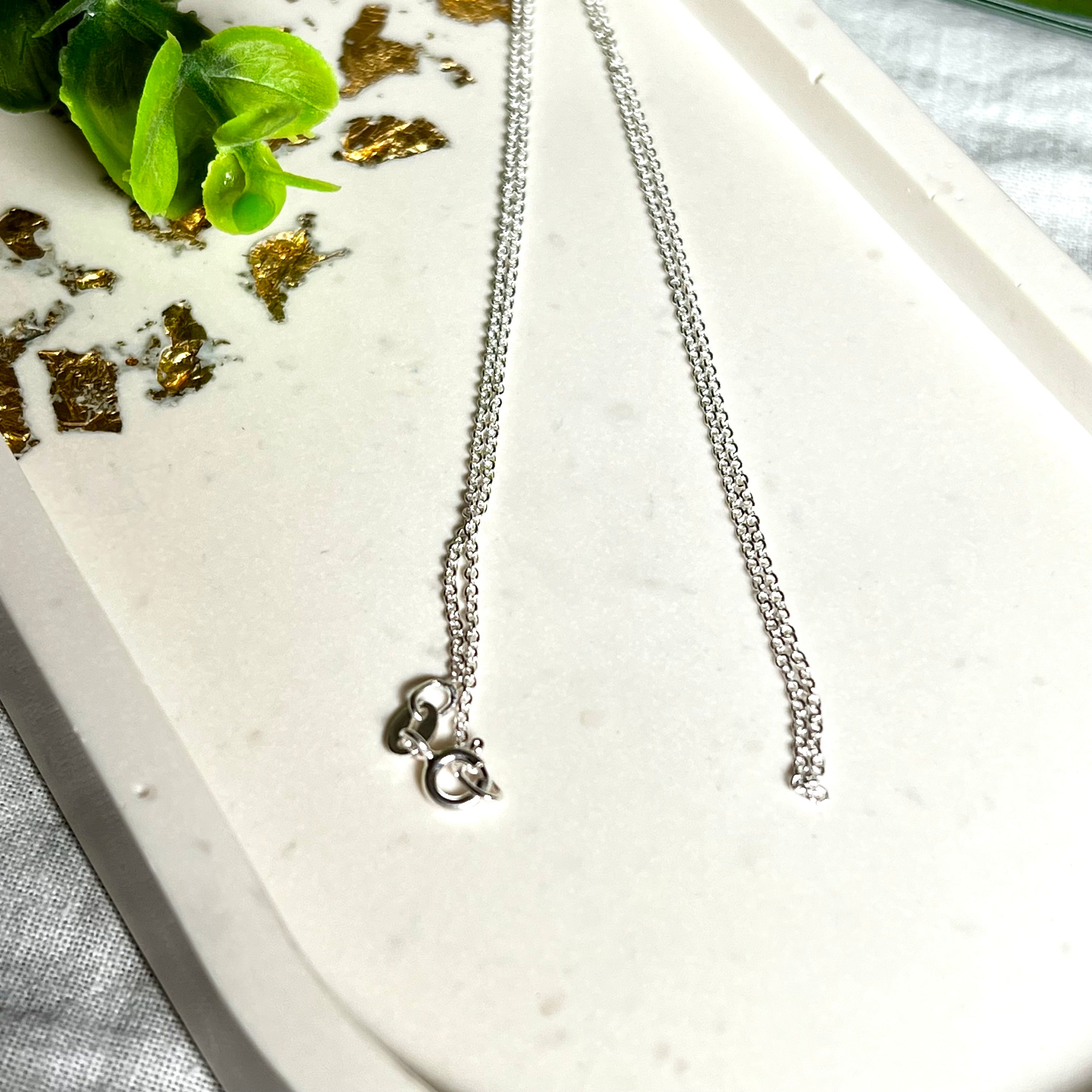 Zarte Ankerkette aus echtem 925 Silber mit klassischem Federring-Verschluss, 1 mm dick, 45 cm lang. Schlichtes, edles Design – ideal für Anhänger oder als feine Solokette. Stilvolle Schmuckfotografie mit natürlichem Hintergrund.