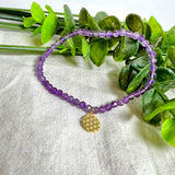 Handgefertigtes Amethyst-Armband mit facettierten 4 mm Edelstein-Perlen in zartem Violett, ergänzt durch einen vergoldeten 925 Silber Charm in Form der Blume des Lebens. Elastisches Design mit ca. 17 cm Innendurchmesser. Elegant, spirituell und fein – ein besonderes Schmuckstück für Achtsamkeit, Energie und Harmonie im Alltag.