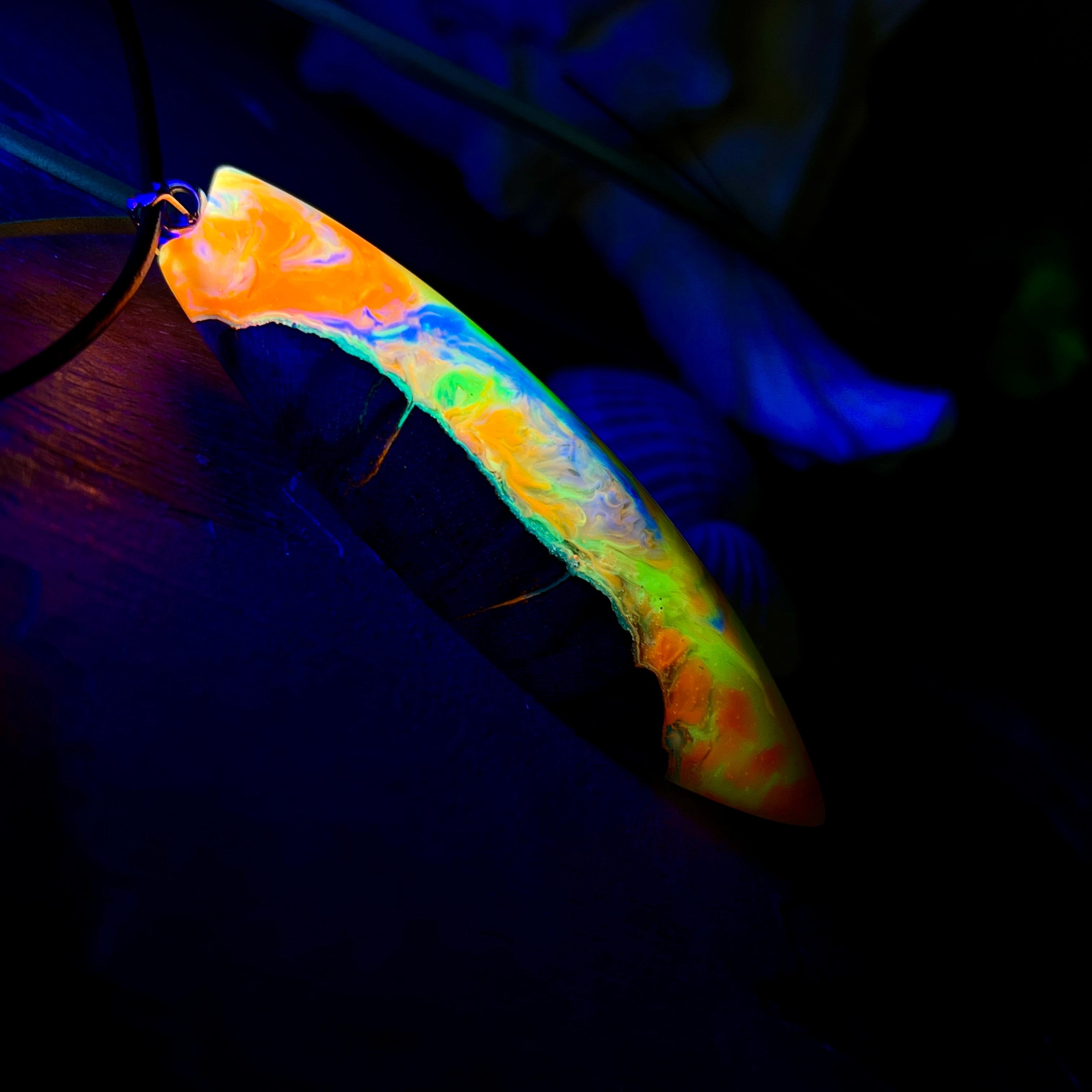 Handgefertigte Halskette „Tropical Glow“ mit Surfbrett-Anhänger aus naturbelassenem Rebholz (Weinrebe) und marmoriertem Epoxidharz in Grün, Orange, Türkis und Weiß. Größe des Anhängers ca. 6,5 × 2 cm. Das Harz fluoresziert eindrucksvoll unter UV-/Schwarzlicht. Edelstahl-Anhängerschlaufe, schwarze Lederkette (45 cm + 5 cm Verlängerung) mit Edelstahl-Karabiner. Unikat in maritim-sommerlichem Stil, ideal als besonderes Geschenk.