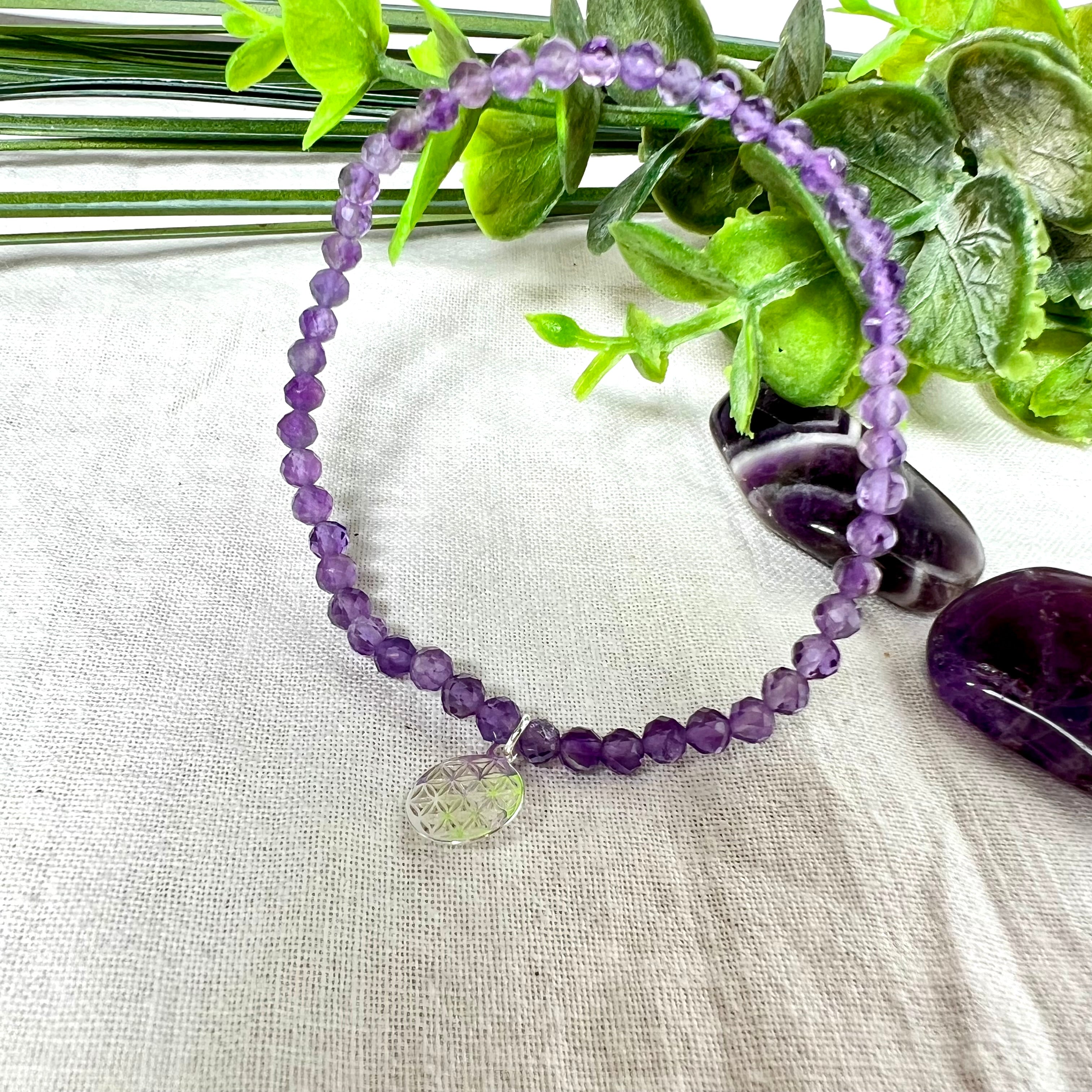 Handgefertigtes Amethyst-Armband aus facettierten 4 mm Edelstein-Perlen mit 925er Silber Charm „Blume des Lebens“. Spirituelles Schmuckstück in zartem Violett. Auf elastischem Gummiband, ca. 17 cm Innendurchmesser. Edles, fein gearbeitetes Design – ideal als Geschenk oder zur eigenen spirituellen Unterstützung.