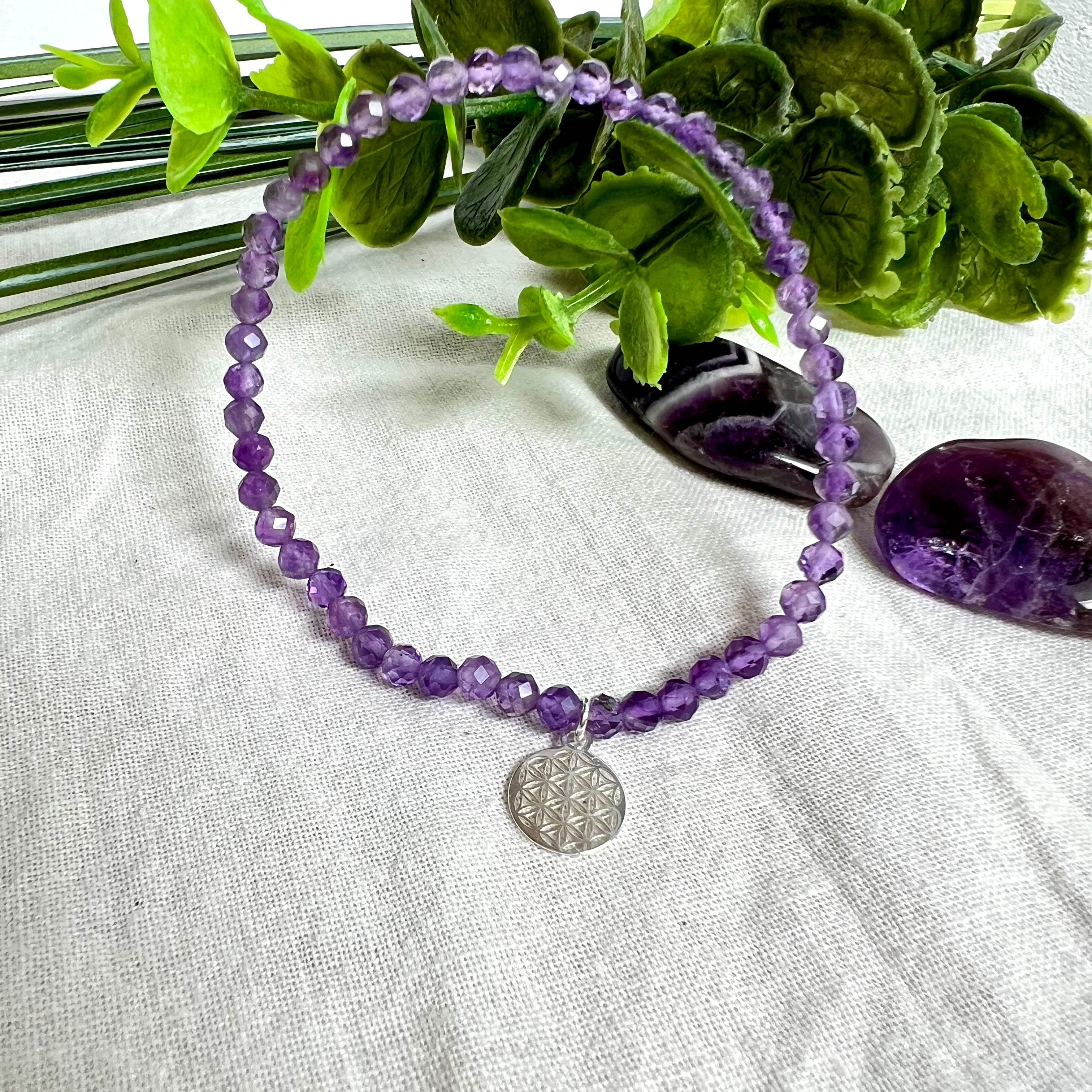 Handgefertigtes Amethyst-Armband aus facettierten 4 mm Edelstein-Perlen mit 925er Silber Charm „Blume des Lebens“. Spirituelles Schmuckstück in zartem Violett. Auf elastischem Gummiband, ca. 17 cm Innendurchmesser. Edles, fein gearbeitetes Design – ideal als Geschenk oder zur eigenen spirituellen Unterstützung.