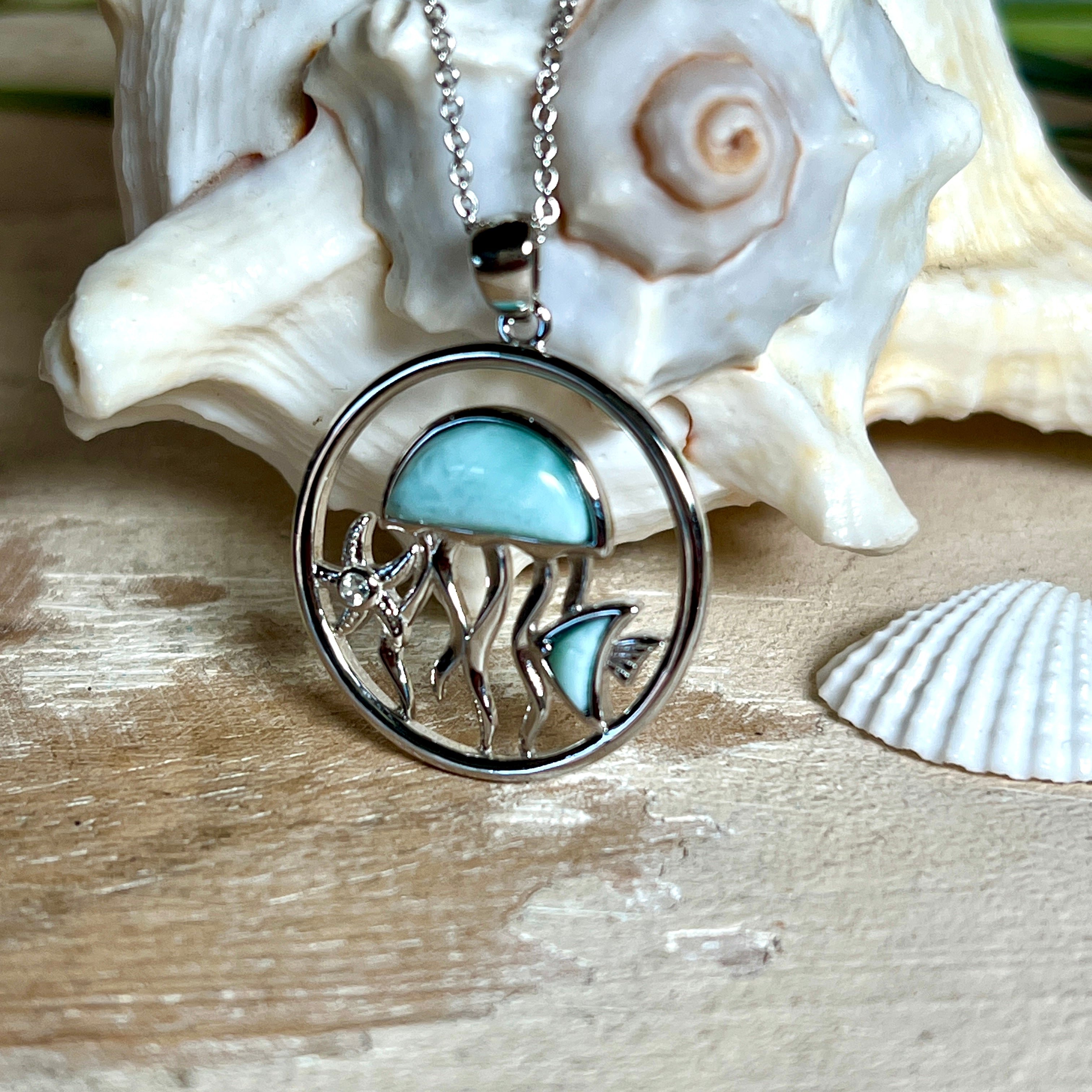 „Sealife“ – runder Anhänger aus rhodiniertem 925 Sterling Silber mit seltenem Larimar und funkelndem Topas. Das maritime Design zeigt eine Qualle, einen Fisch und einen Seestern. Anhängergröße ca. 32 × 26 mm, inklusive 45 cm langer Silberkette (1 mm Stärke). Symbol für die Schönheit und Vielfalt des Ozeans – jedes Stück ein Unikat durch das natürliche Farbspiel des Larimars.