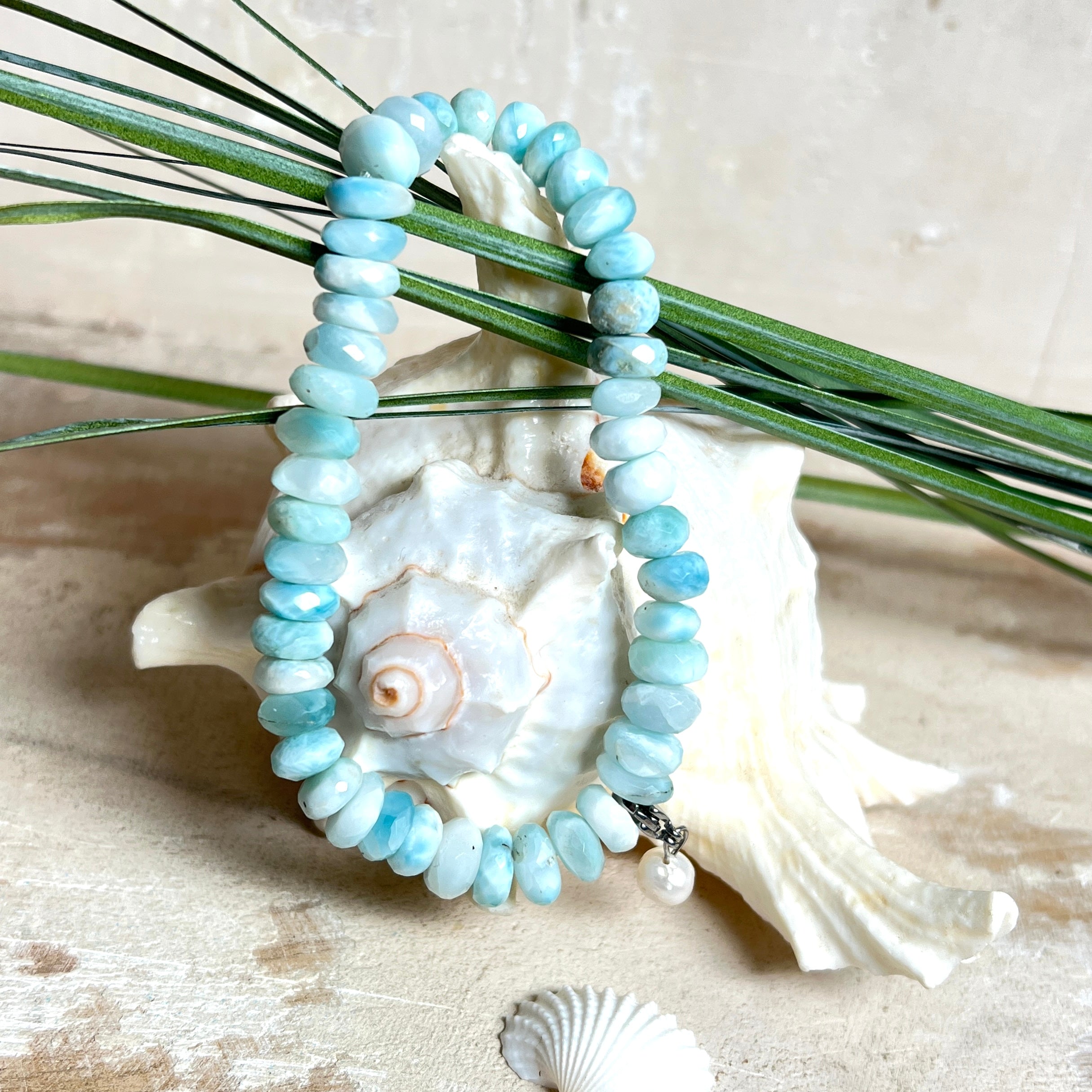 Handgefertigtes Armband aus seltenem Larimar mit facettierten, türkis-blauen Edelsteinperlen (Ø ca. 6–7 mm), elastischem Band und einem zarten Süßwasserperlen-Charm an Edelstahlkarabiner. Der wertvolle Larimar, auch „Stein des Atlantis“ genannt, gilt als Edelstein der Ruhe und Meeresverbundenheit.