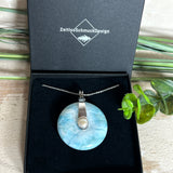 Echter Larimar-Donut (42 mm) mit Süßwasserperle, gefasst in rhodiniertem 925 Sterlingsilber. Mit 45 cm langer, rhodinierter Silberkette. Selten, edel & handgefertigt – inspiriert vom Blau der Karibik.