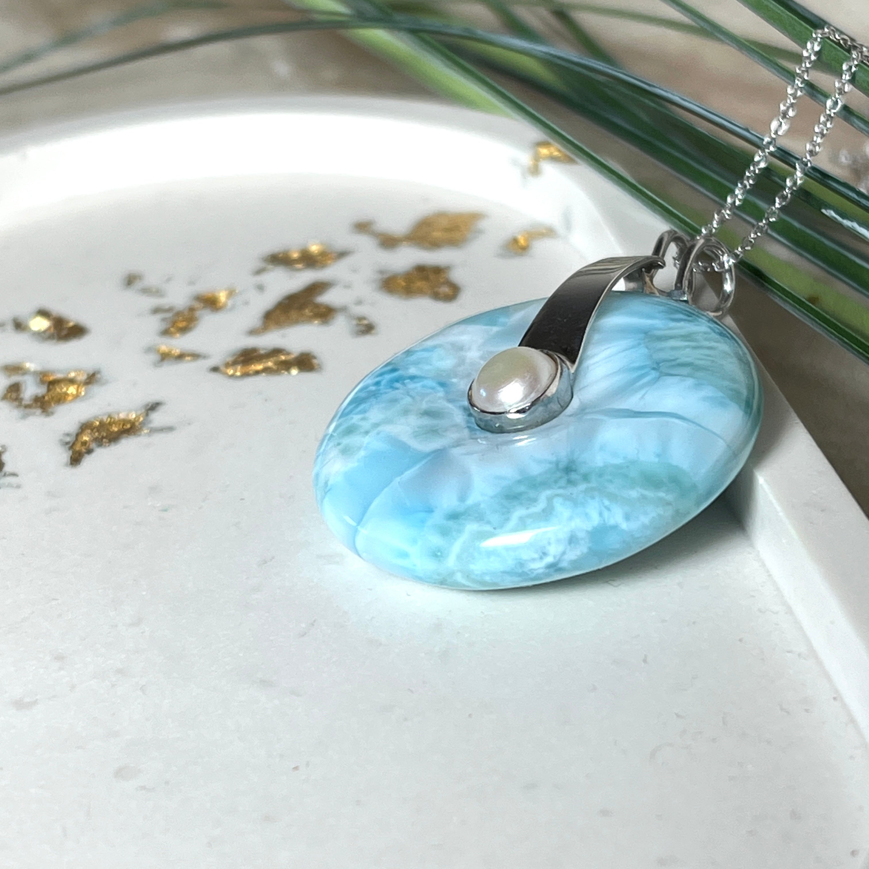 Echter Larimar-Donut (42 mm) mit Süßwasserperle, gefasst in rhodiniertem 925 Sterlingsilber. Mit 45 cm langer, rhodinierter Silberkette. Selten, edel & handgefertigt – inspiriert vom Blau der Karibik.