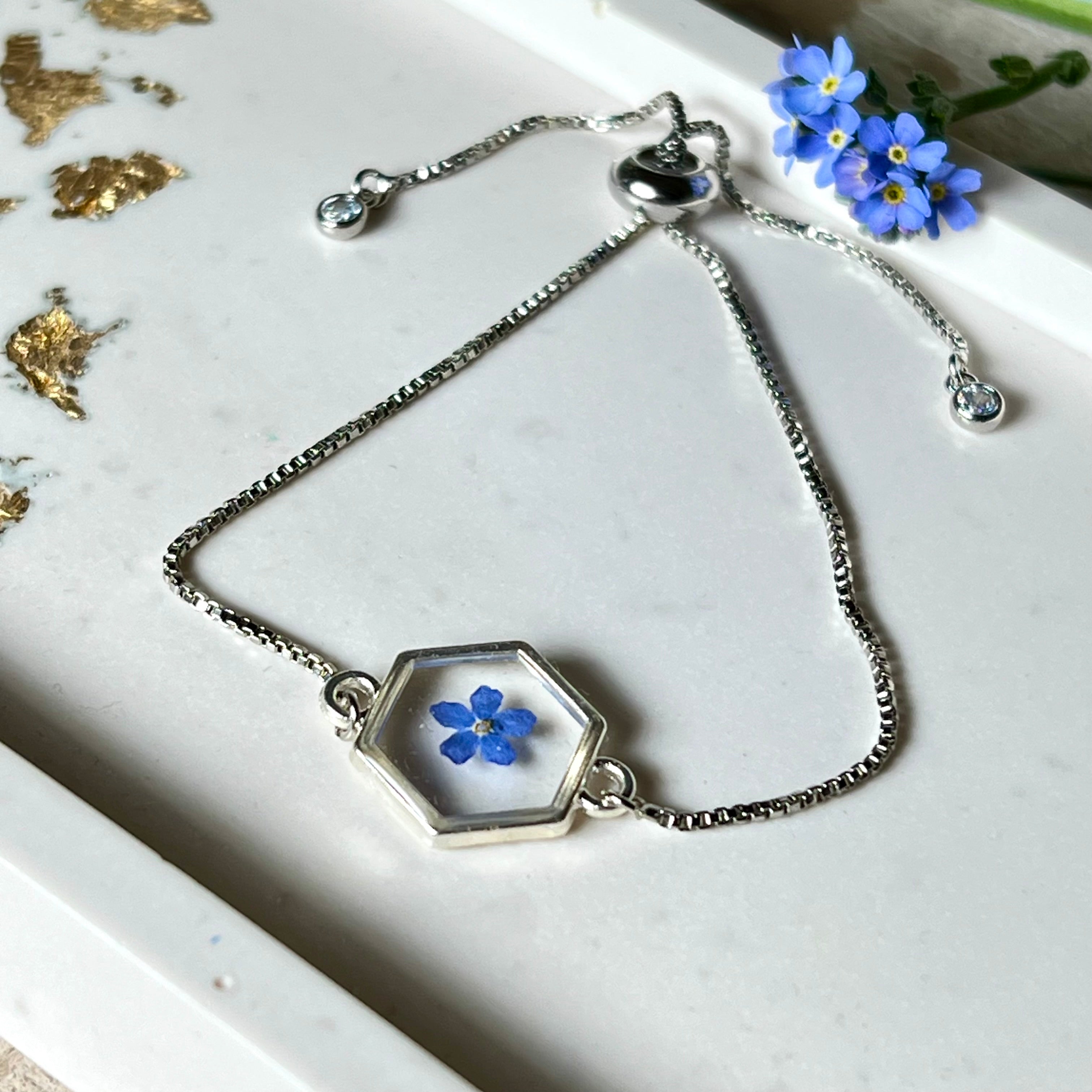 „Handgefertigtes Armband mit echter Vergissmeinnicht-Blume, eingebettet in klares Harz. Verstellbares Edelstahlarmband mit Schiebeverschluss und funkelnden Zirkonia-Endperlen. Symbolträchtiger Schmuck für Frauen – ideal als Geschenk zum Muttertag, Geburtstag oder zur Erinnerung an einen besonderen Menschen.“