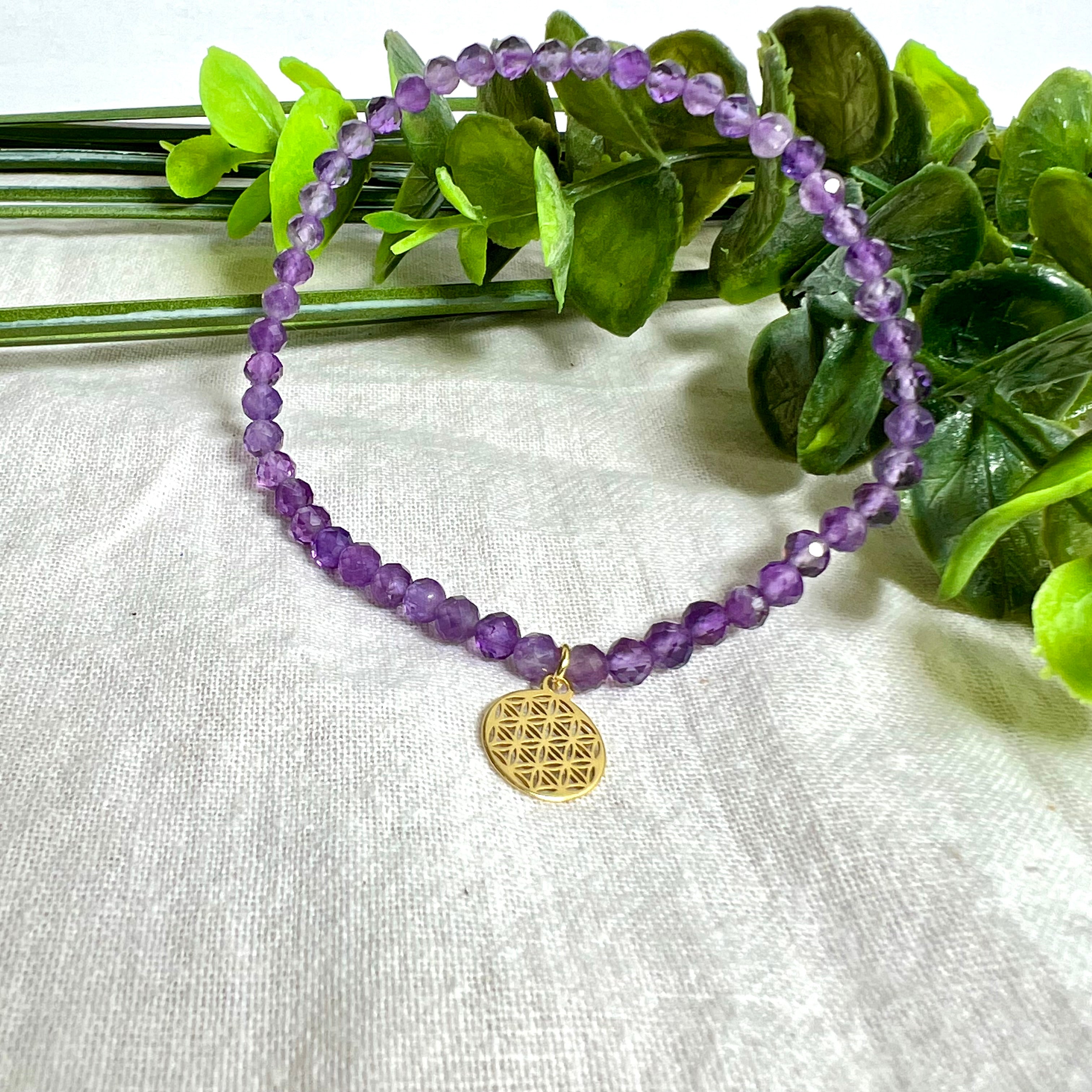 Handgefertigtes Amethyst-Armband mit facettierten 4 mm Edelstein-Perlen in zartem Violett, ergänzt durch einen vergoldeten 925 Silber Charm in Form der Blume des Lebens. Elastisches Design mit ca. 17 cm Innendurchmesser. Elegant, spirituell und fein – ein besonderes Schmuckstück für Achtsamkeit, Energie und Harmonie im Alltag.