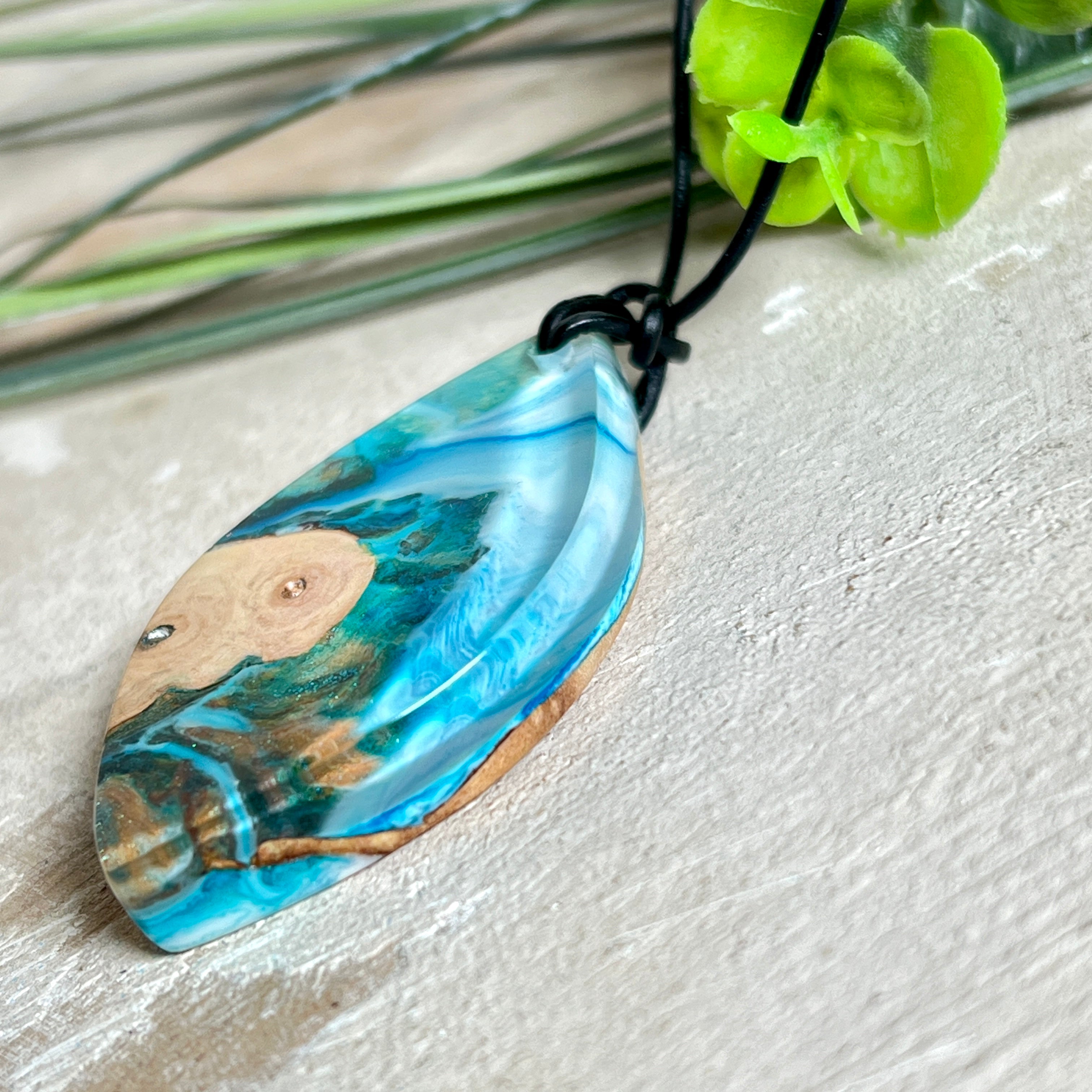 Handgefertigter Anhänger „Ocean Leaf“ aus Maserholz und Epoxidharz in Blau- und Türkistönen. Ein einzigartiges Schmuckstück, das die Schönheit von Natur und Meer einfängt. Mit verstellbarem Lederband (24–43 cm). Jeder Anhänger ist ein Unikat mit einzigartiger Maserung und Farbverlauf.