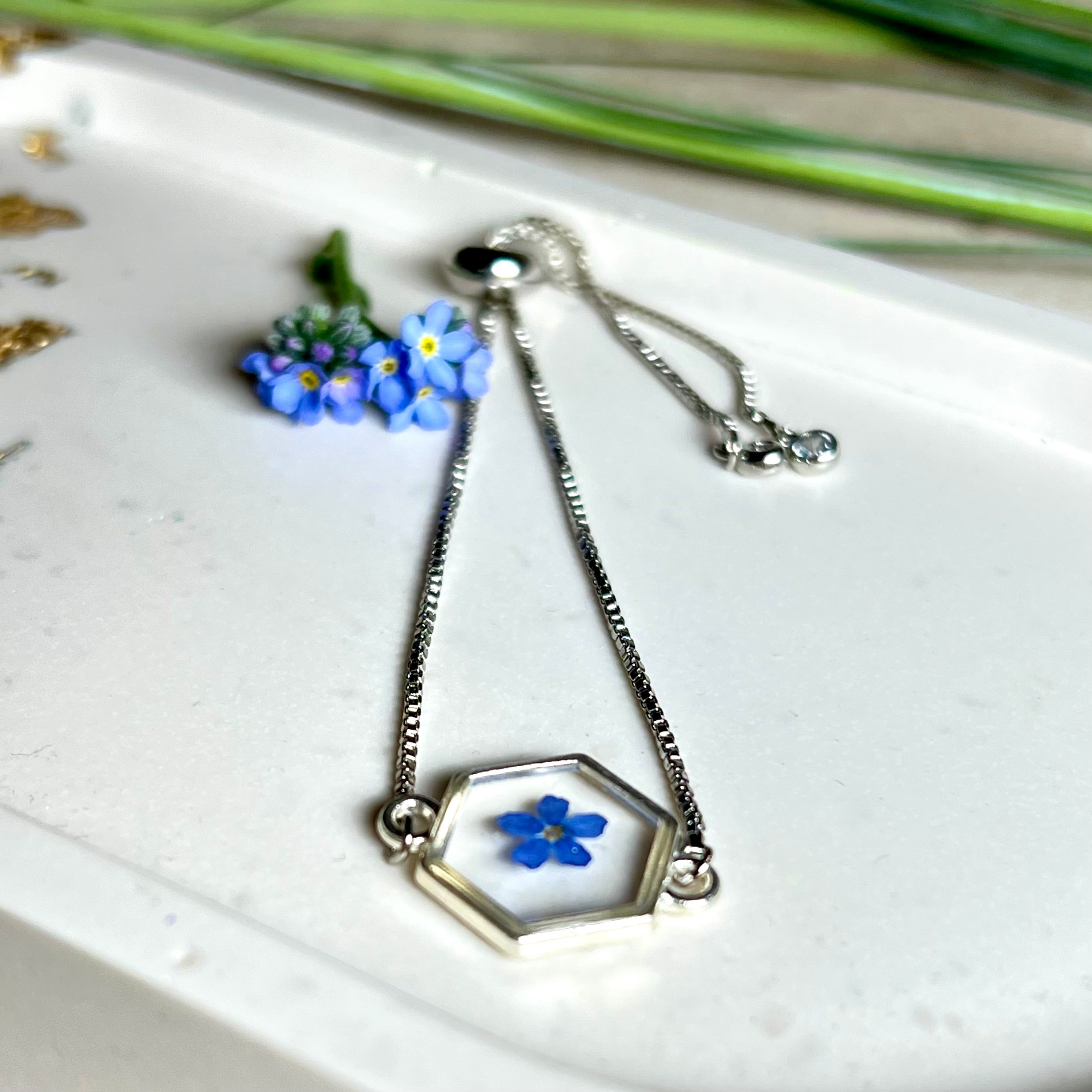 „Handgefertigtes Armband mit echter Vergissmeinnicht-Blume, eingebettet in klares Harz. Verstellbares Edelstahlarmband mit Schiebeverschluss und funkelnden Zirkonia-Endperlen. Symbolträchtiger Schmuck für Frauen – ideal als Geschenk zum Muttertag, Geburtstag oder zur Erinnerung an einen besonderen Menschen.“