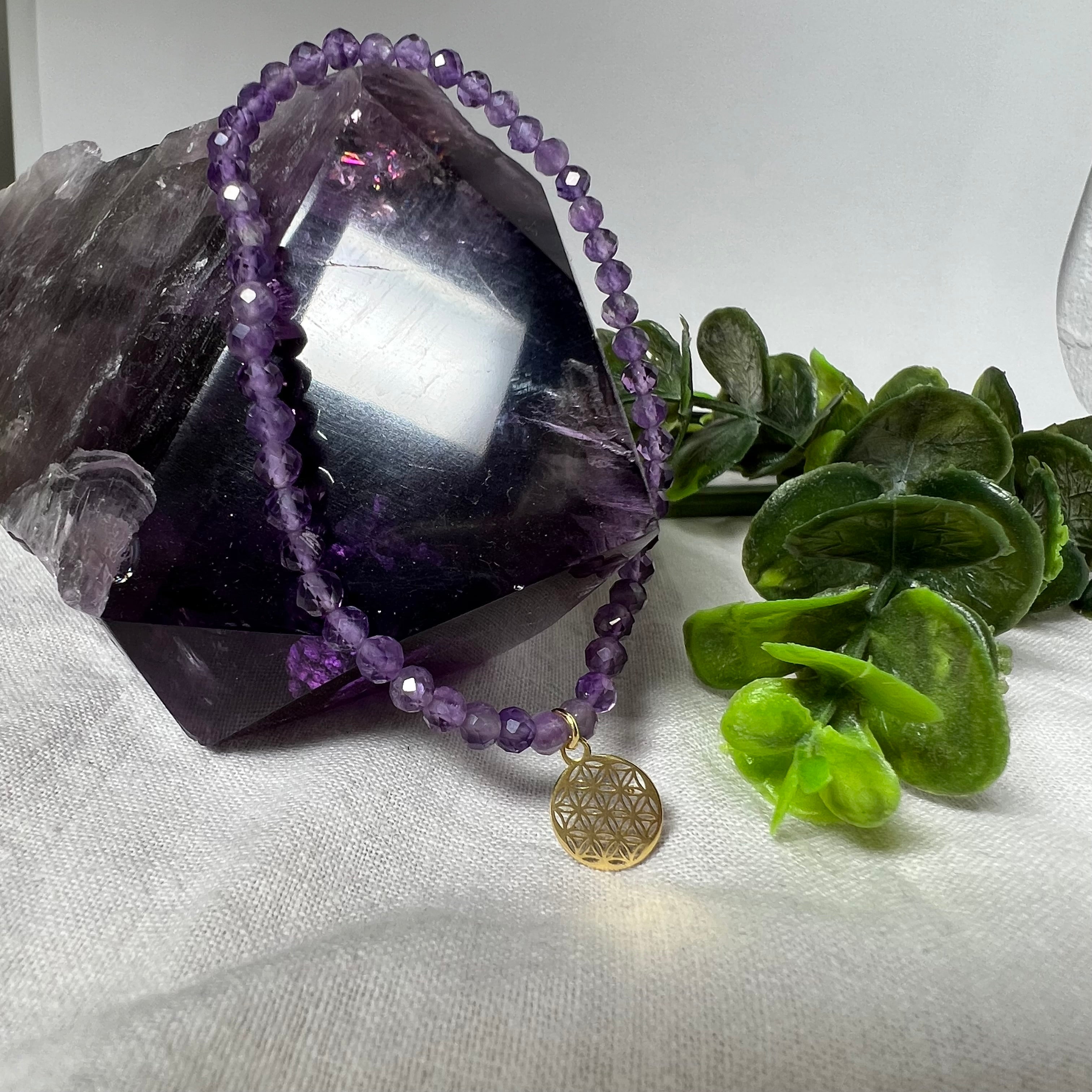 Handgefertigtes Amethyst-Armband mit facettierten 4 mm Edelstein-Perlen in zartem Violett, ergänzt durch einen vergoldeten 925 Silber Charm in Form der Blume des Lebens. Elastisches Design mit ca. 17 cm Innendurchmesser. Elegant, spirituell und fein – ein besonderes Schmuckstück für Achtsamkeit, Energie und Harmonie im Alltag.