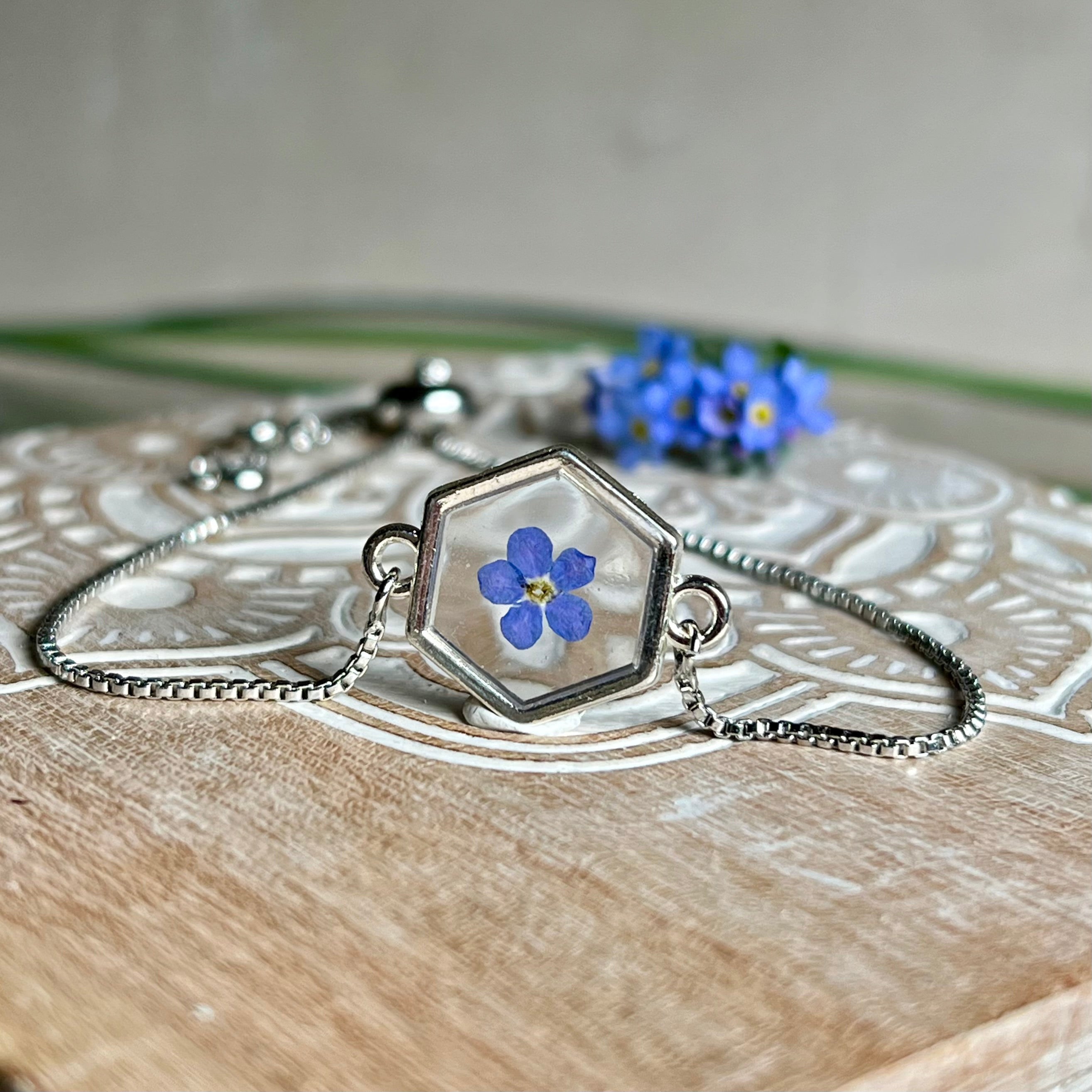 „Handgefertigtes Armband mit echter Vergissmeinnicht-Blume, eingebettet in klares Harz. Verstellbares Edelstahlarmband mit Schiebeverschluss und funkelnden Zirkonia-Endperlen. Symbolträchtiger Schmuck für Frauen – ideal als Geschenk zum Muttertag, Geburtstag oder zur Erinnerung an einen besonderen Menschen.“