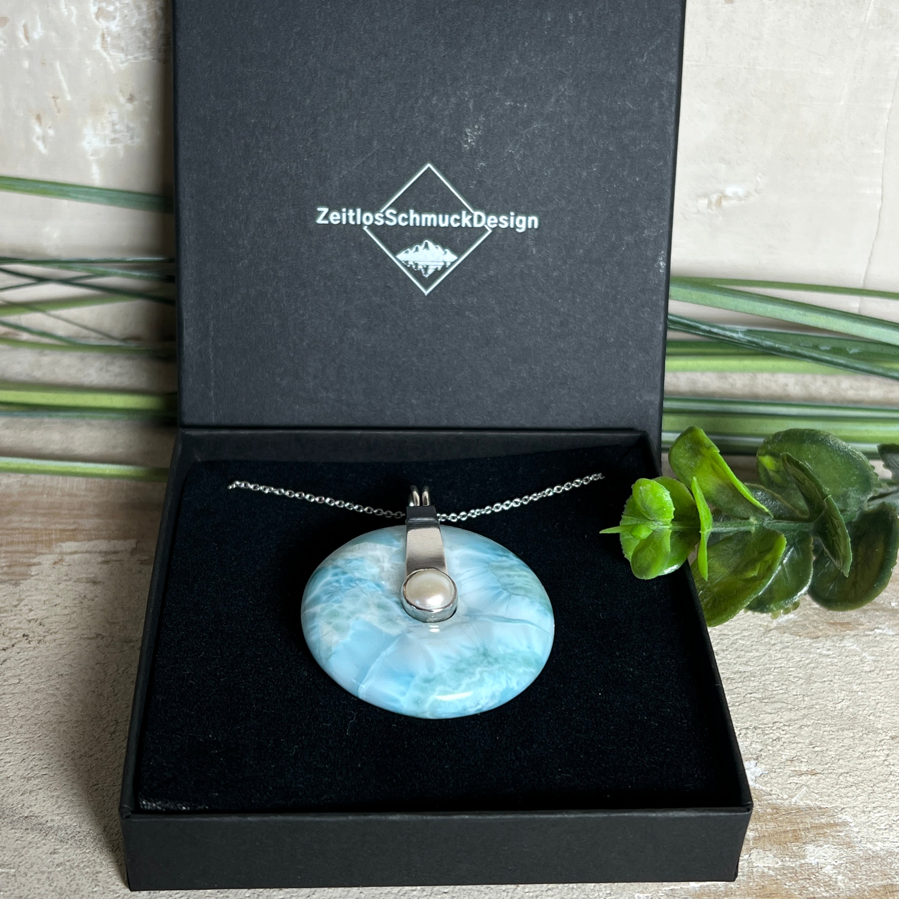 Echter Larimar-Donut (42 mm) mit Süßwasserperle, gefasst in rhodiniertem 925 Sterlingsilber. Mit 45 cm langer, rhodinierter Silberkette. Selten, edel & handgefertigt – inspiriert vom Blau der Karibik.