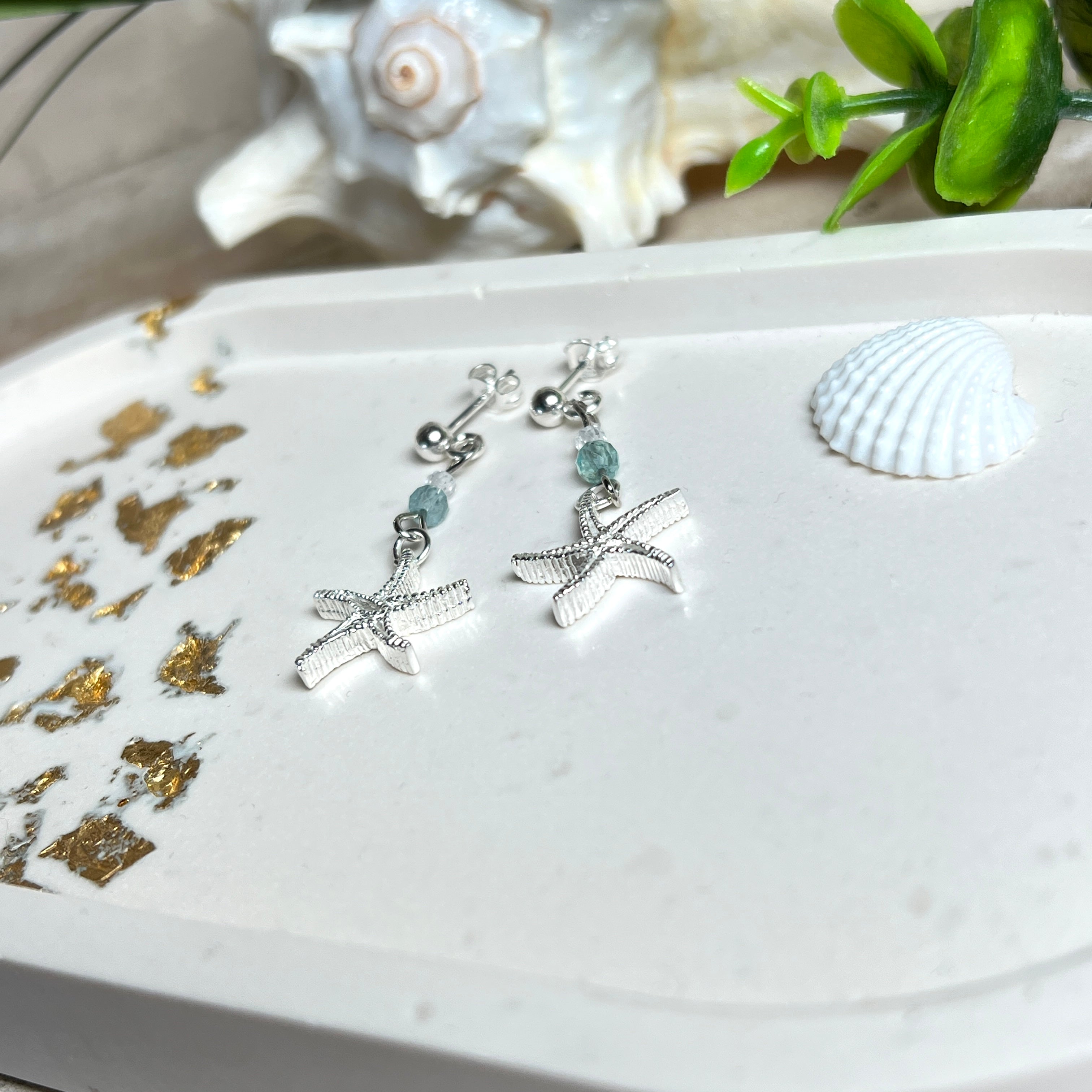 Edle „Ocean Star“ Ohrringe aus 925 Sterling Silber mit Seestern-Anhängern (18 × 17 mm), verziert mit einer aquablauen Apatitperle und funkelndem Zirkonia. Länge getragen: 45 mm. Maritime Schmuckstücke, die das Funkeln des Meeres einfangen – elegant, hochwertig und ein ideales Geschenk für Meeresliebhaber und Sommerträume.