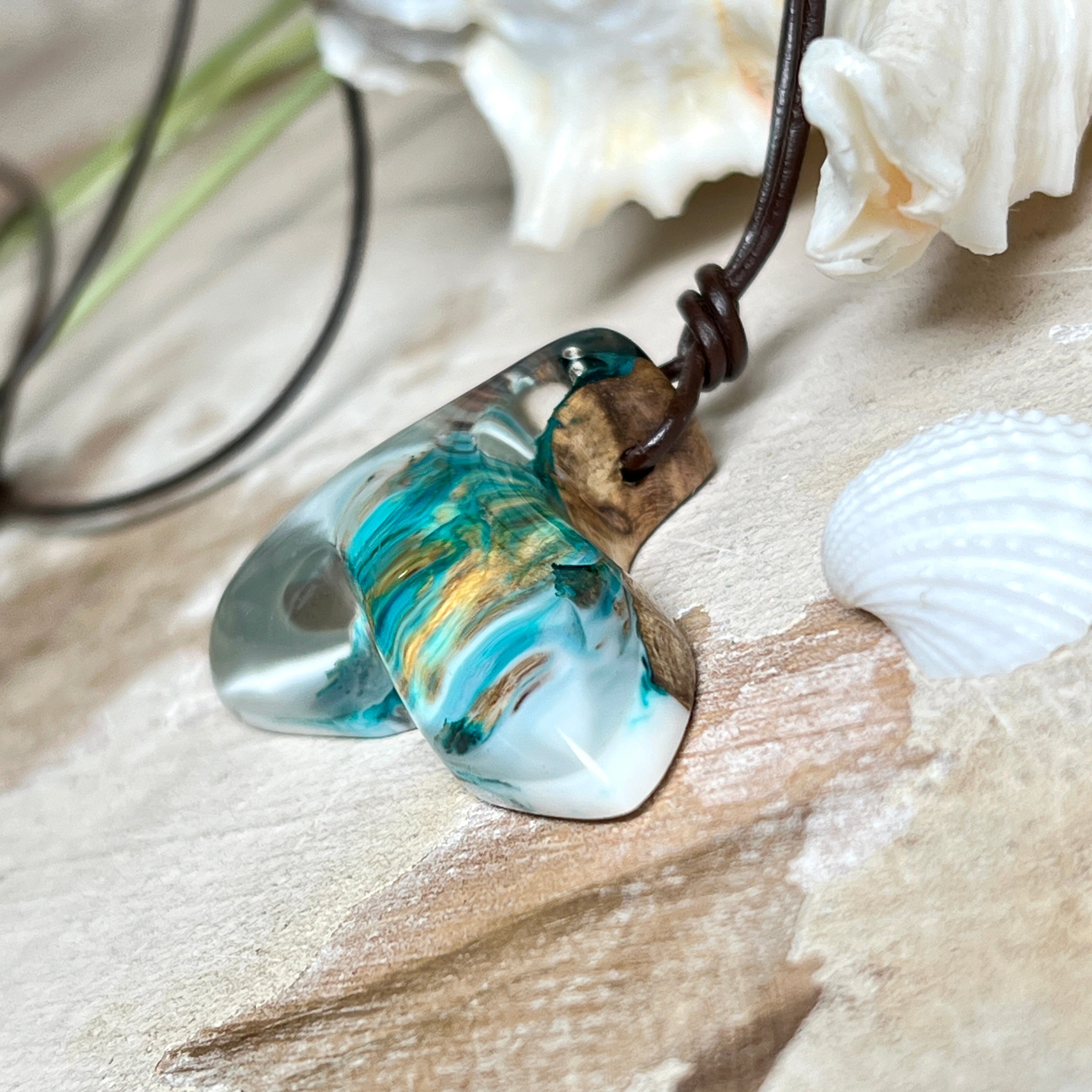 Walflossen-Anhänger „Flossenklang“ – handgefertigtes Unikat aus Maserholz und türkis-blau-grauen und weißem Harz. Die elegant geschwungene Form erinnert an die Flosse eines Wals und symbolisiert Freiheit, Stärke und Naturverbundenheit. Mit verstellbarem braunem Lederband gefertigt, ist jedes Stück ein individuelles Schmuckstück für Meeresliebhaber und Natursuchende. Maritimer Halsschmuck, inspiriert vom Ozean, glatt poliert und mit Liebe zum Detail von Hand gearbeitet.