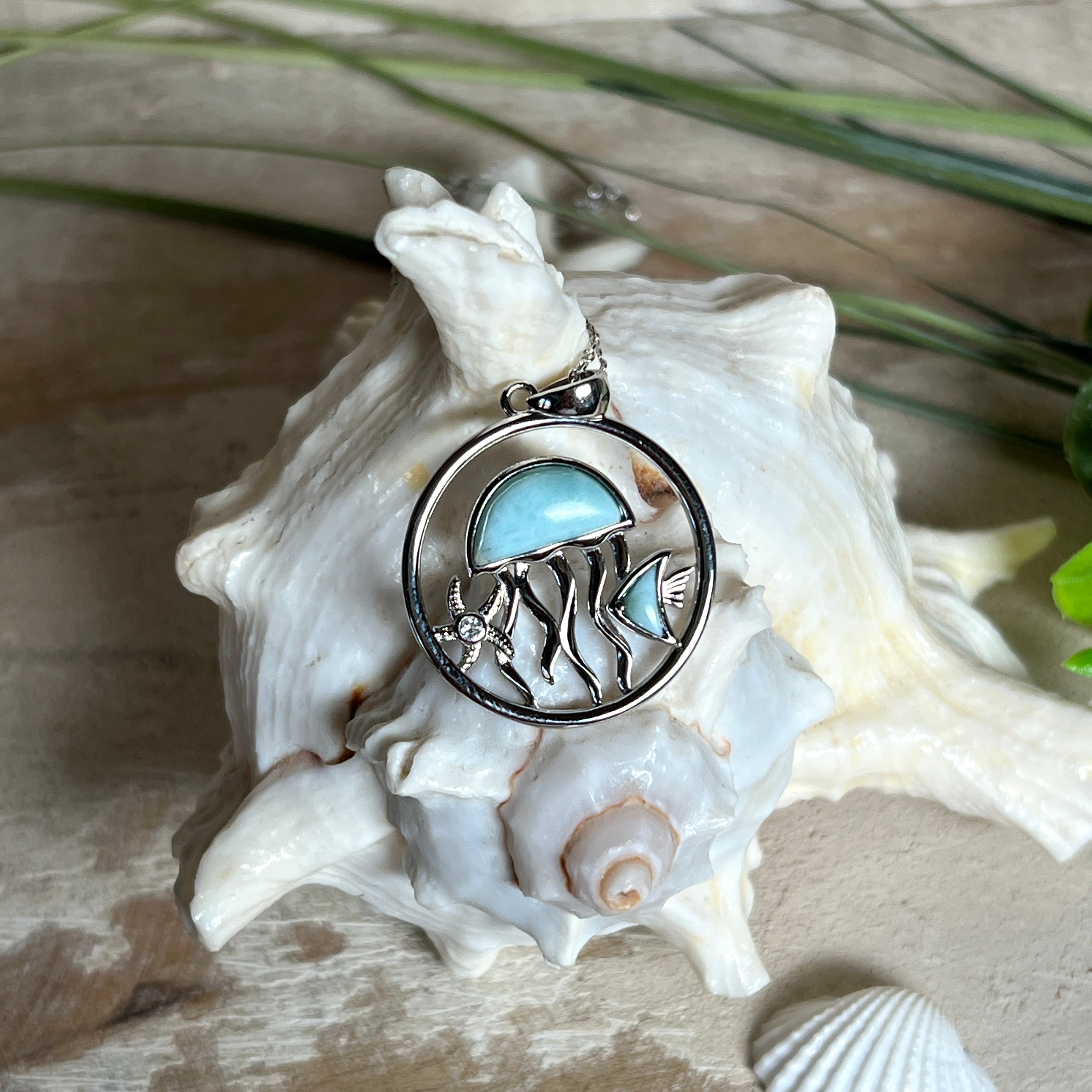 „Sealife“ – runder Anhänger aus rhodiniertem 925 Sterling Silber mit seltenem Larimar und funkelndem Topas. Das maritime Design zeigt eine Qualle, einen Fisch und einen Seestern. Anhängergröße ca. 32 × 26 mm, inklusive 45 cm langer Silberkette (1 mm Stärke). Symbol für die Schönheit und Vielfalt des Ozeans – jedes Stück ein Unikat durch das natürliche Farbspiel des Larimars.