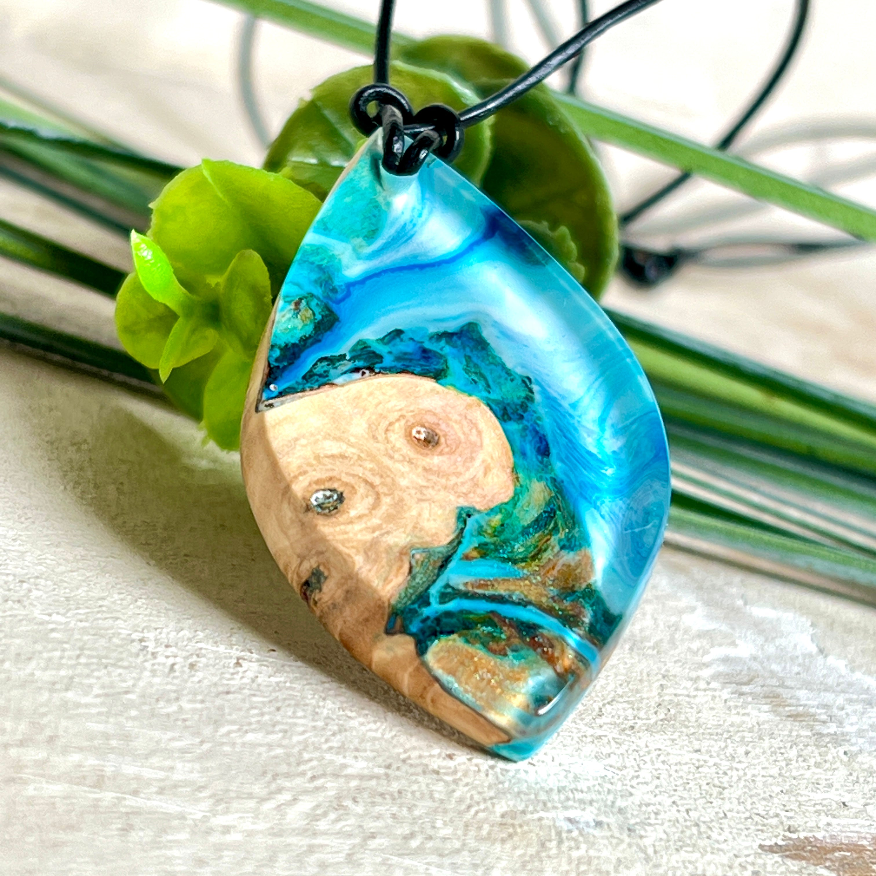 Handgefertigter Anhänger „Ocean Leaf“ aus Maserholz und Epoxidharz in Blau- und Türkistönen. Ein einzigartiges Schmuckstück, das die Schönheit von Natur und Meer einfängt. Mit verstellbarem Lederband (24–43 cm). Jeder Anhänger ist ein Unikat mit einzigartiger Maserung und Farbverlauf.