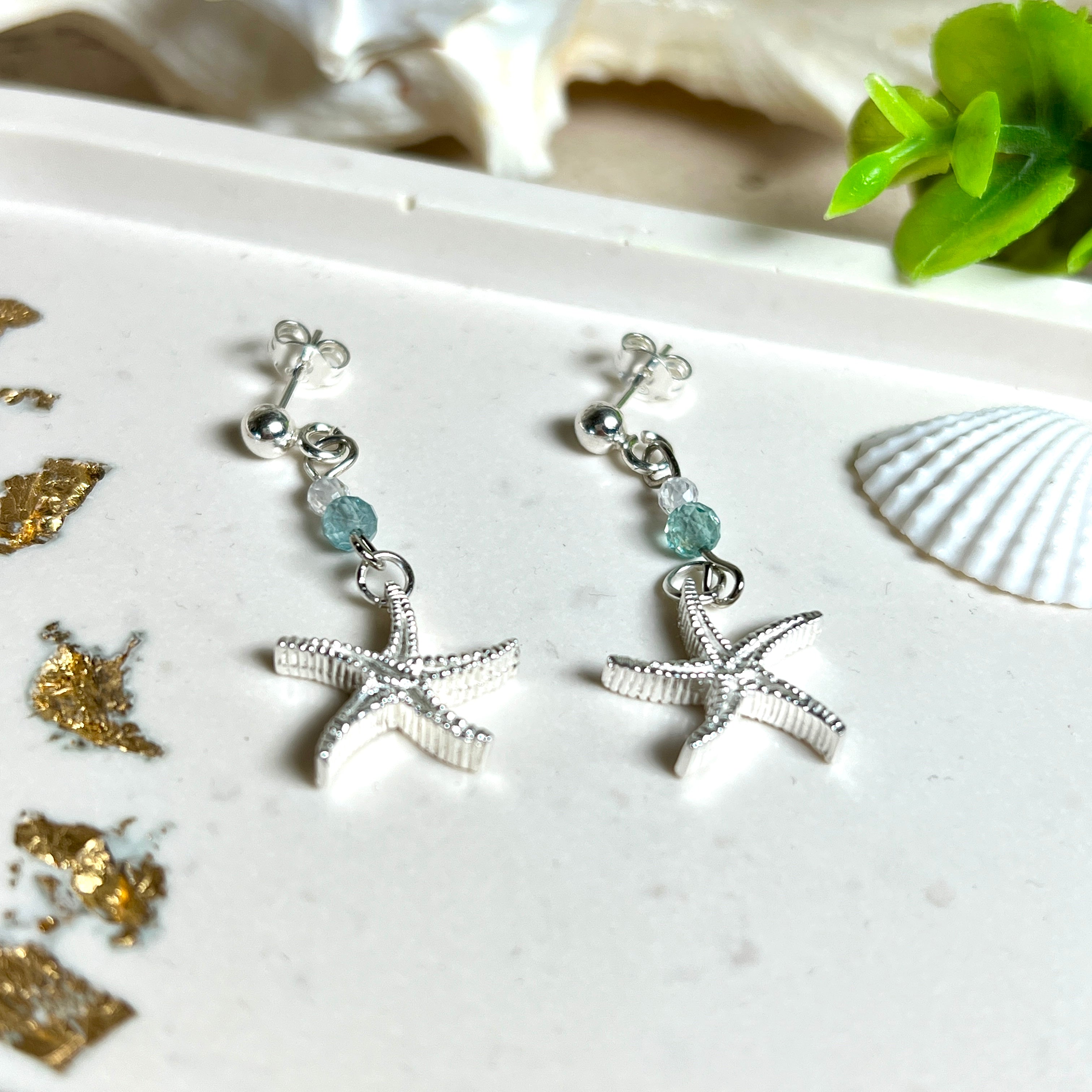 Edle „Ocean Star“ Ohrringe aus 925 Sterling Silber mit Seestern-Anhängern (18 × 17 mm), verziert mit einer aquablauen Apatitperle und funkelndem Zirkonia. Länge getragen: 45 mm. Maritime Schmuckstücke, die das Funkeln des Meeres einfangen – elegant, hochwertig und ein ideales Geschenk für Meeresliebhaber und Sommerträume.