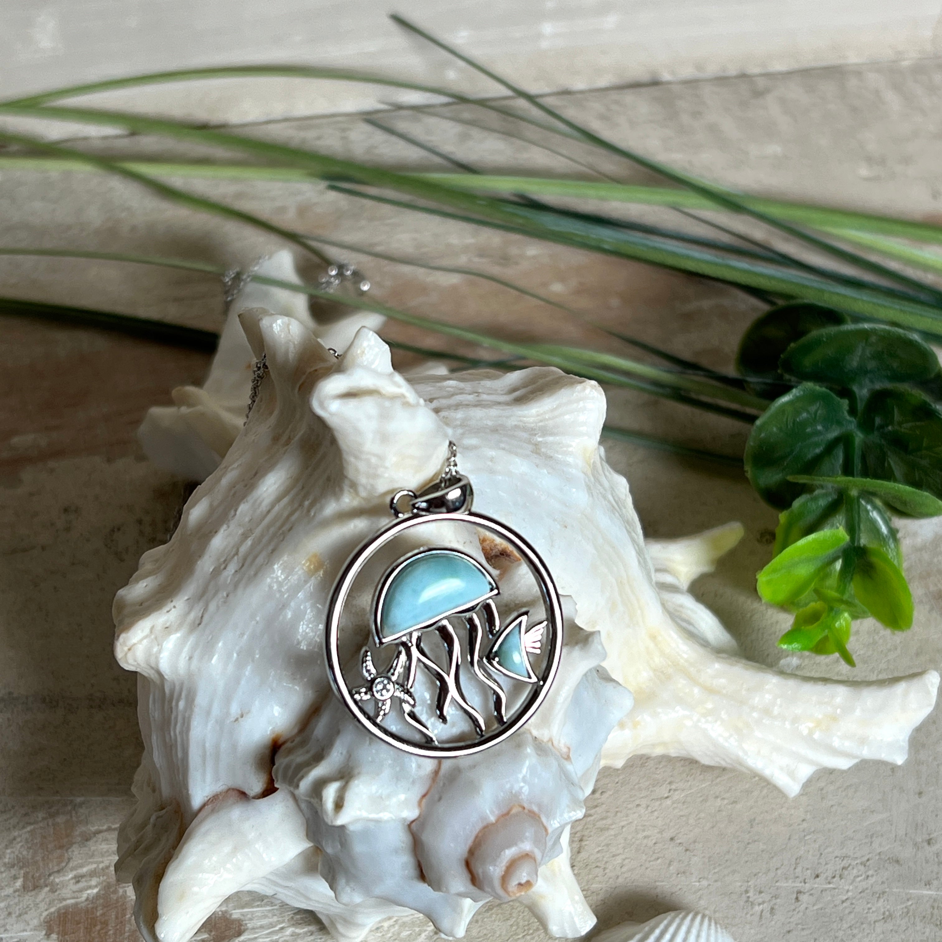 „Sealife“ – runder Anhänger aus rhodiniertem 925 Sterling Silber mit seltenem Larimar und funkelndem Topas. Das maritime Design zeigt eine Qualle, einen Fisch und einen Seestern. Anhängergröße ca. 32 × 26 mm, inklusive 45 cm langer Silberkette (1 mm Stärke). Symbol für die Schönheit und Vielfalt des Ozeans – jedes Stück ein Unikat durch das natürliche Farbspiel des Larimars.