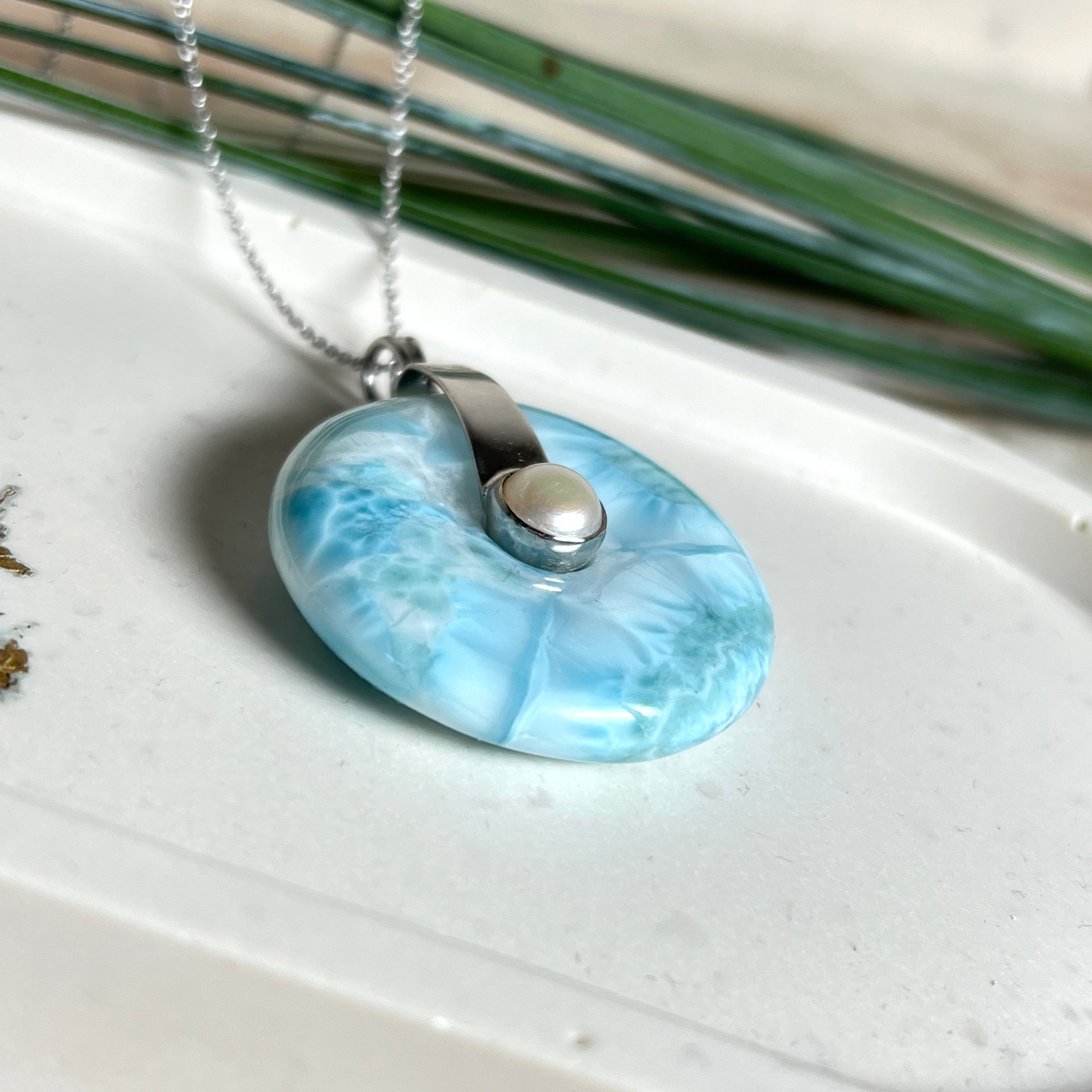 Echter Larimar-Donut (42 mm) mit Süßwasserperle, gefasst in rhodiniertem 925 Sterlingsilber. Mit 45 cm langer, rhodinierter Silberkette. Selten, edel & handgefertigt – inspiriert vom Blau der Karibik.