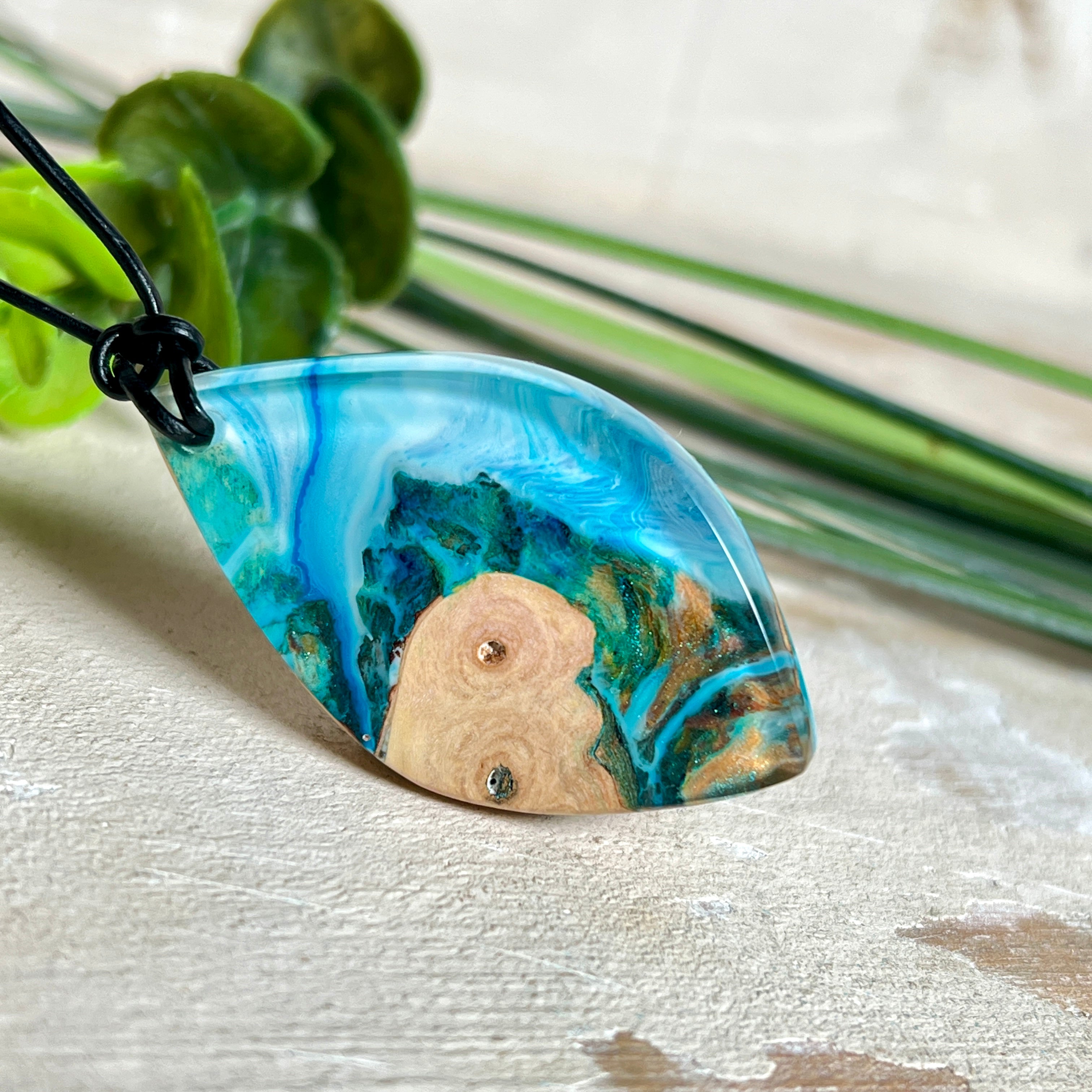 Handgefertigter Anhänger „Ocean Leaf“ aus Maserholz und Epoxidharz in Blau- und Türkistönen. Ein einzigartiges Schmuckstück, das die Schönheit von Natur und Meer einfängt. Mit verstellbarem Lederband (24–43 cm). Jeder Anhänger ist ein Unikat mit einzigartiger Maserung und Farbverlauf.