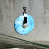 Echter Larimar-Donut (42 mm) mit Süßwasserperle, gefasst in rhodiniertem 925 Sterlingsilber. Mit 45 cm langer, rhodinierter Silberkette. Selten, edel & handgefertigt – inspiriert vom Blau der Karibik.