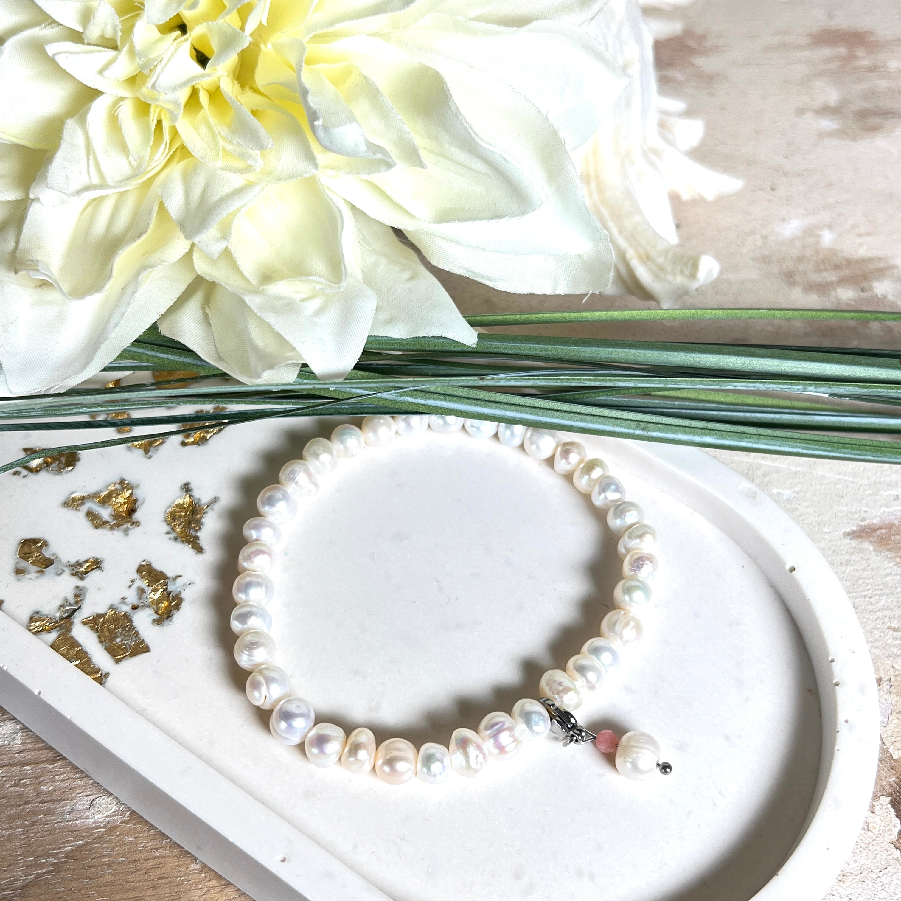 Handgefertigtes Armband „Ocean Bloom“ mit echten, schimmernden Süßwasserperlen (Ø ca. 6–7 mm) auf elastischem Band. Jede Perle ist ein Unikat mit natürlicher Form und sanftem Glanz. Highlight: Charmanhänger mit einer Süßwasserperle und einer facettierten Andenopal-Perle, befestigt an einem robusten Edelstahl-Karabiner. Ein Schmuckstück voller Eleganz, Symbolkraft und maritimer Schönheit.