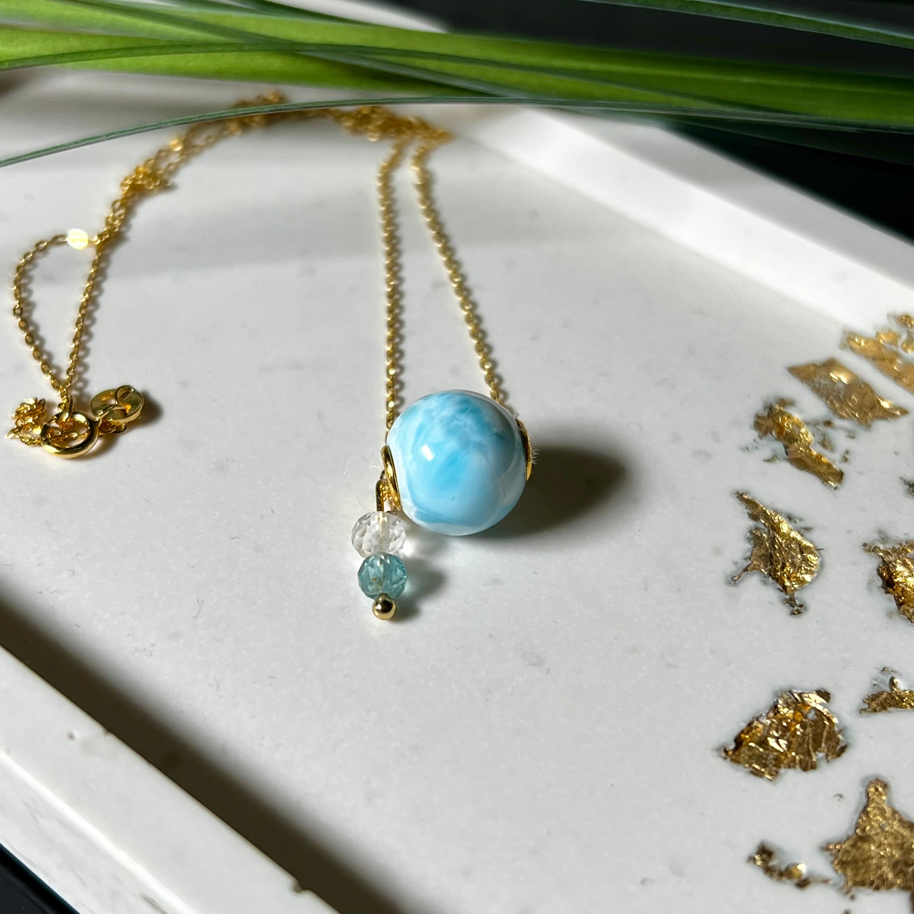 Feine Halskette aus 925er Silber vergoldet mit einer polierten Larimar-Perle als Hauptstein, ergänzt durch funkelnde Apatit- und Bergkristall-Perlen. Der Edelstein mit seiner typischen Meeresfärbung erinnert an tropische Lagunen und steht für innere Ruhe und Klarheit.Ideal als Geschenk zum Geburtstag, für Meerliebhaber oder spirituelle Schmuckträgerinnen.